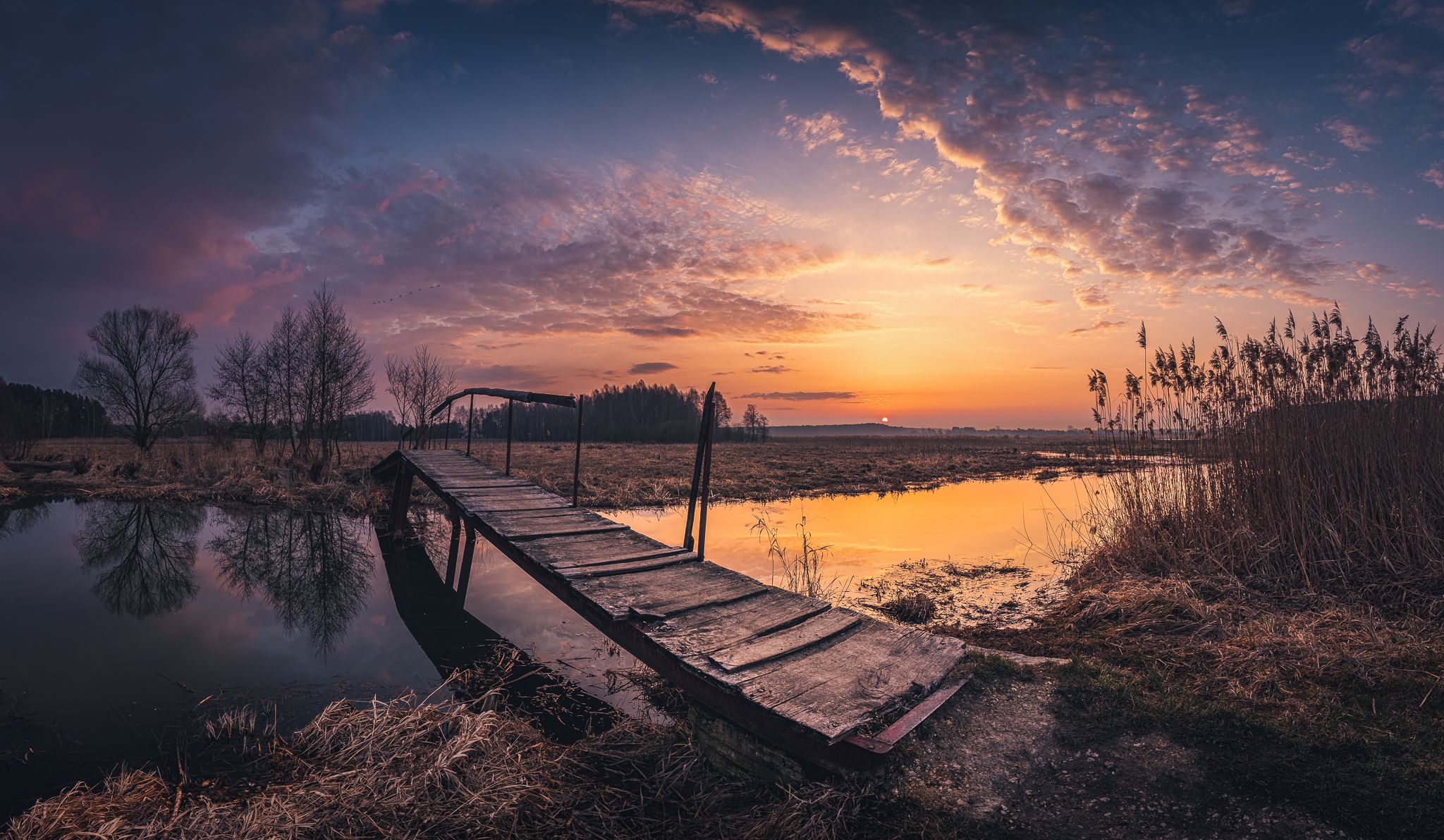 2048x1192 Sunset Serenity: Rustic Bridge Over Tranquil Waters HD Wallpaper by Michał Tomczak