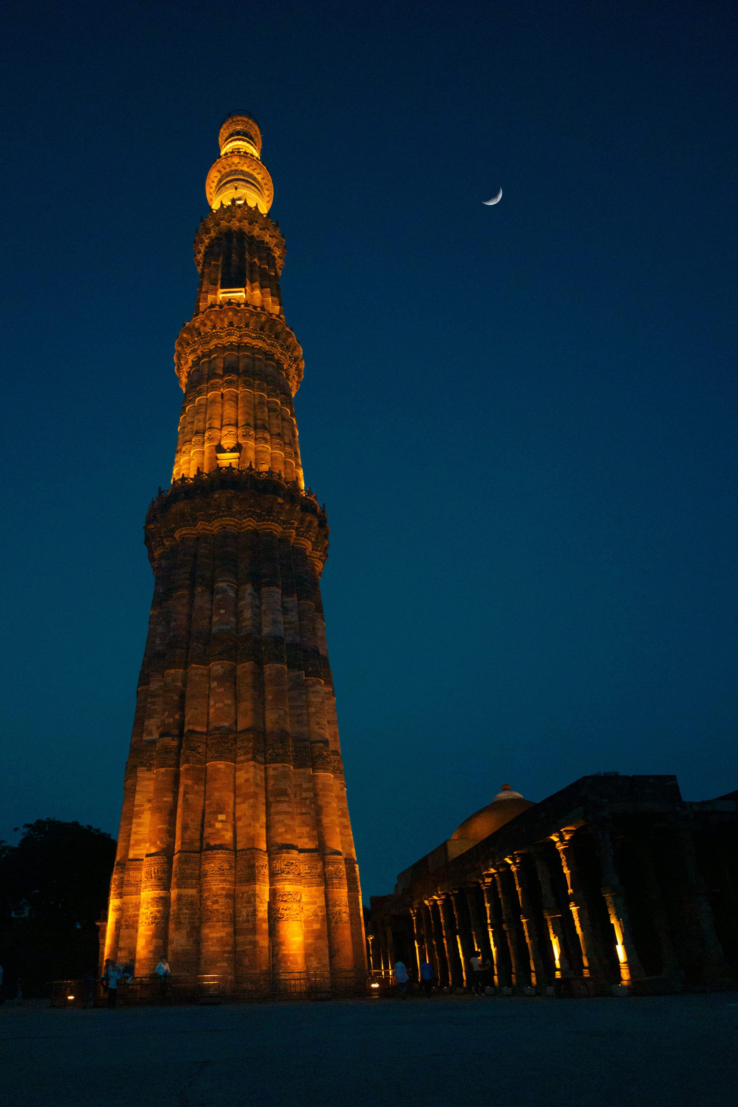 3000x4500 A tall tower with lights at night with Qutub Minar in the background photo
