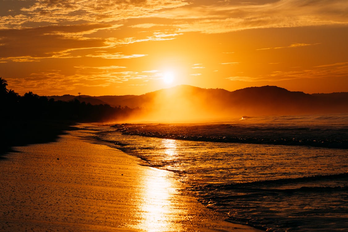 1125x750 Serene Sunset Over Ocean Beach with Golden Hues · Free
