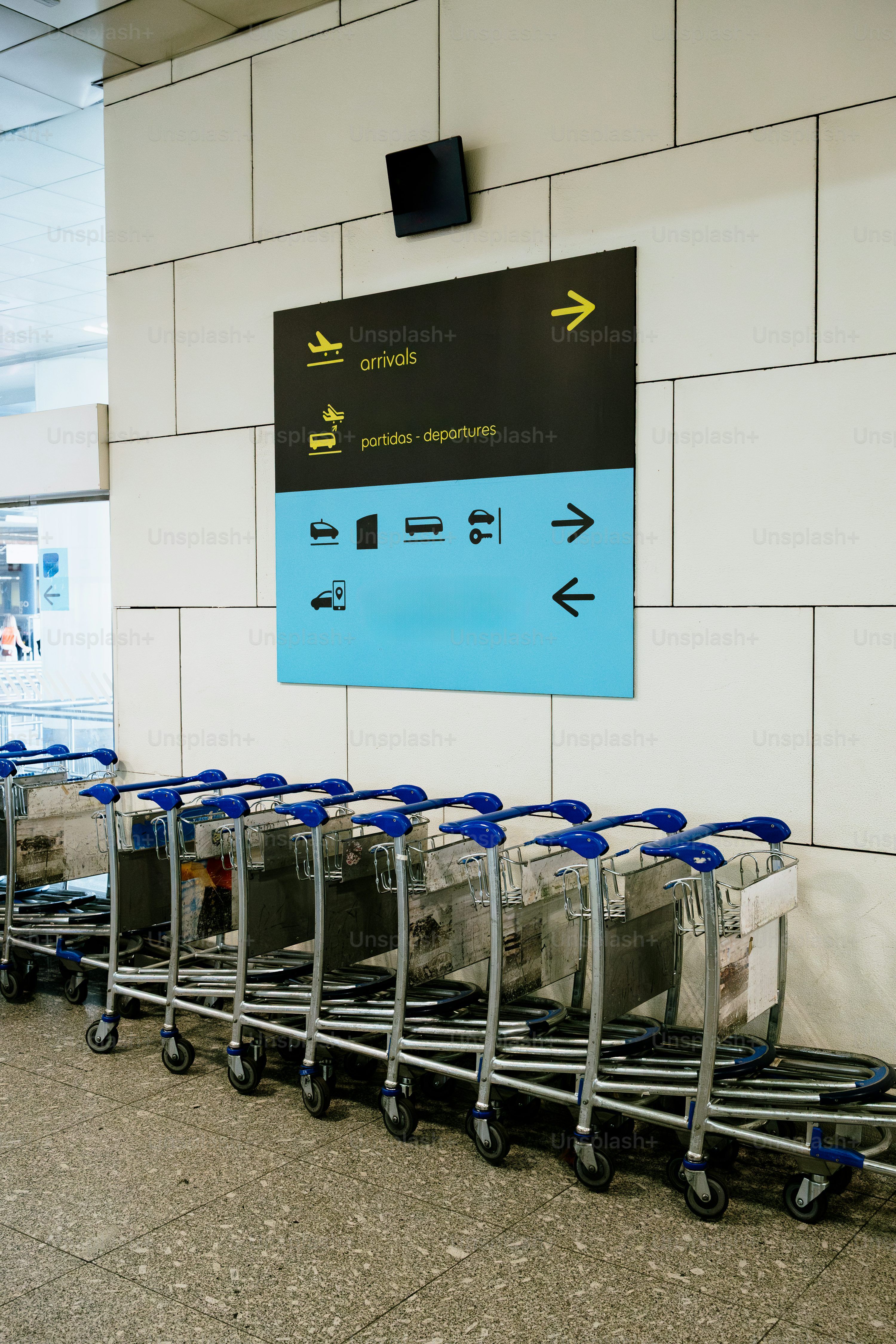 3000x4500 Luggage carts lined up near airport signage photo
