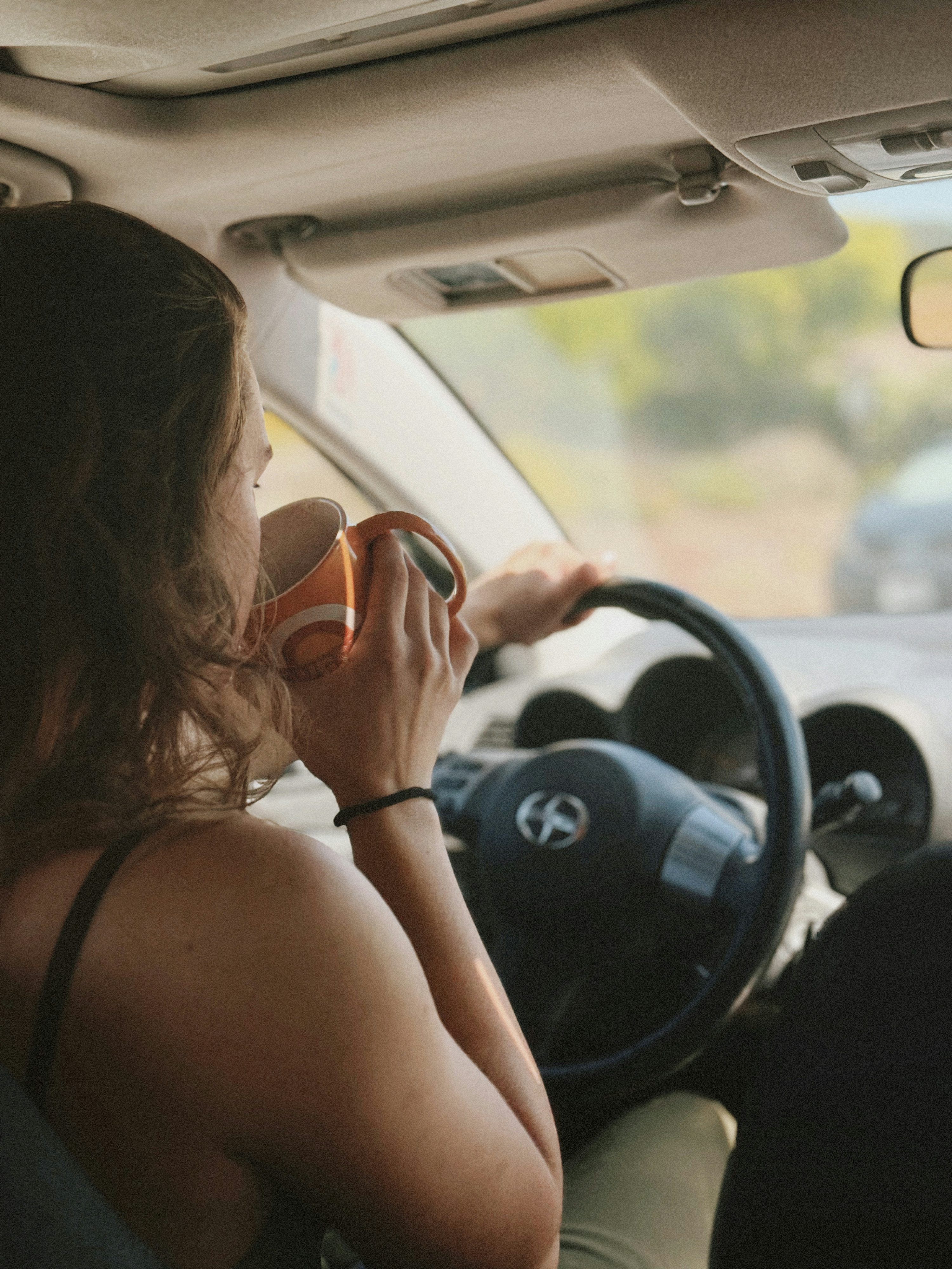 3000x4000 Woman drinking coffee while driving a car photo