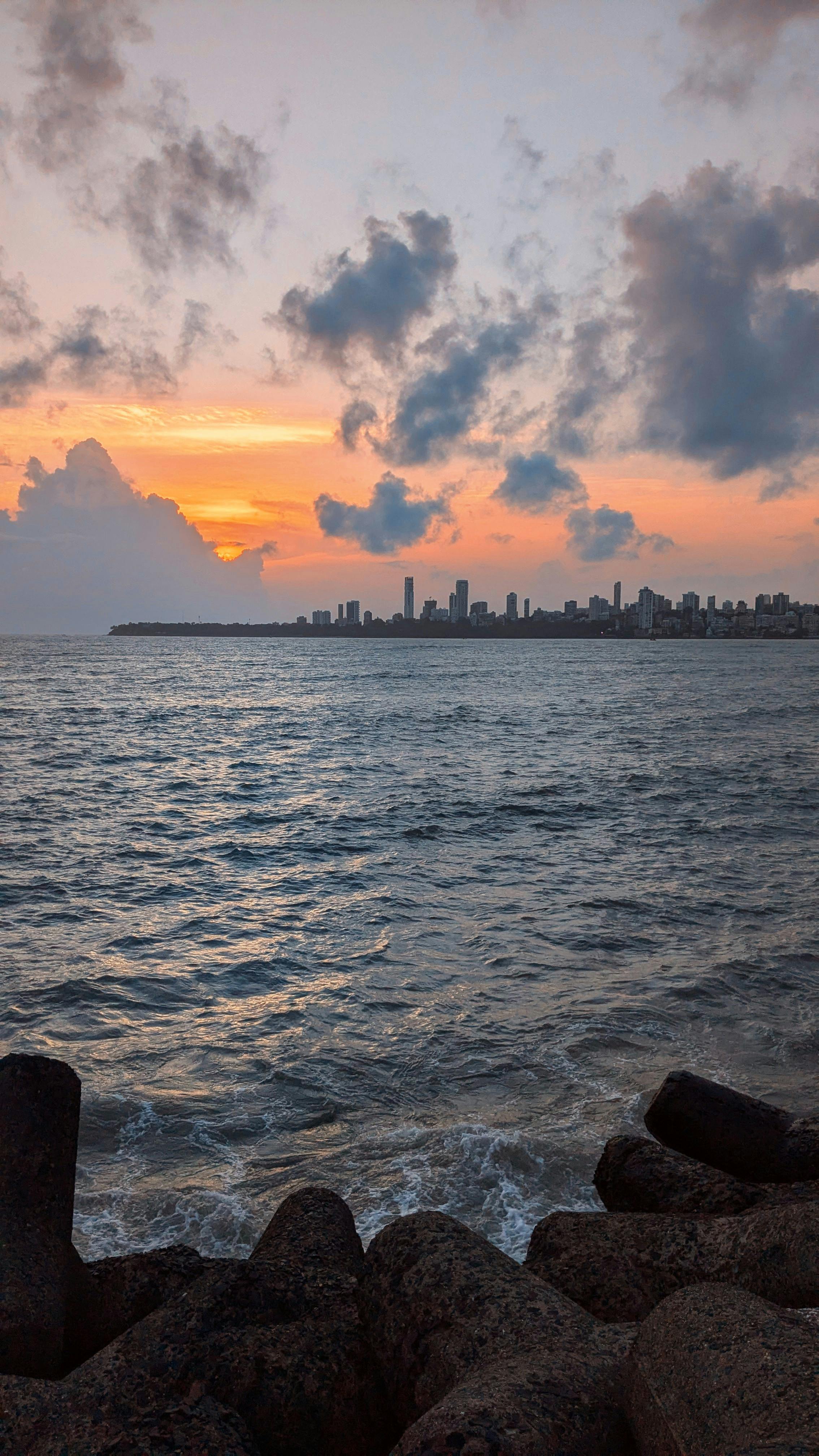 2268x4032 A sunset over the ocean with a city skyline in the background · Free