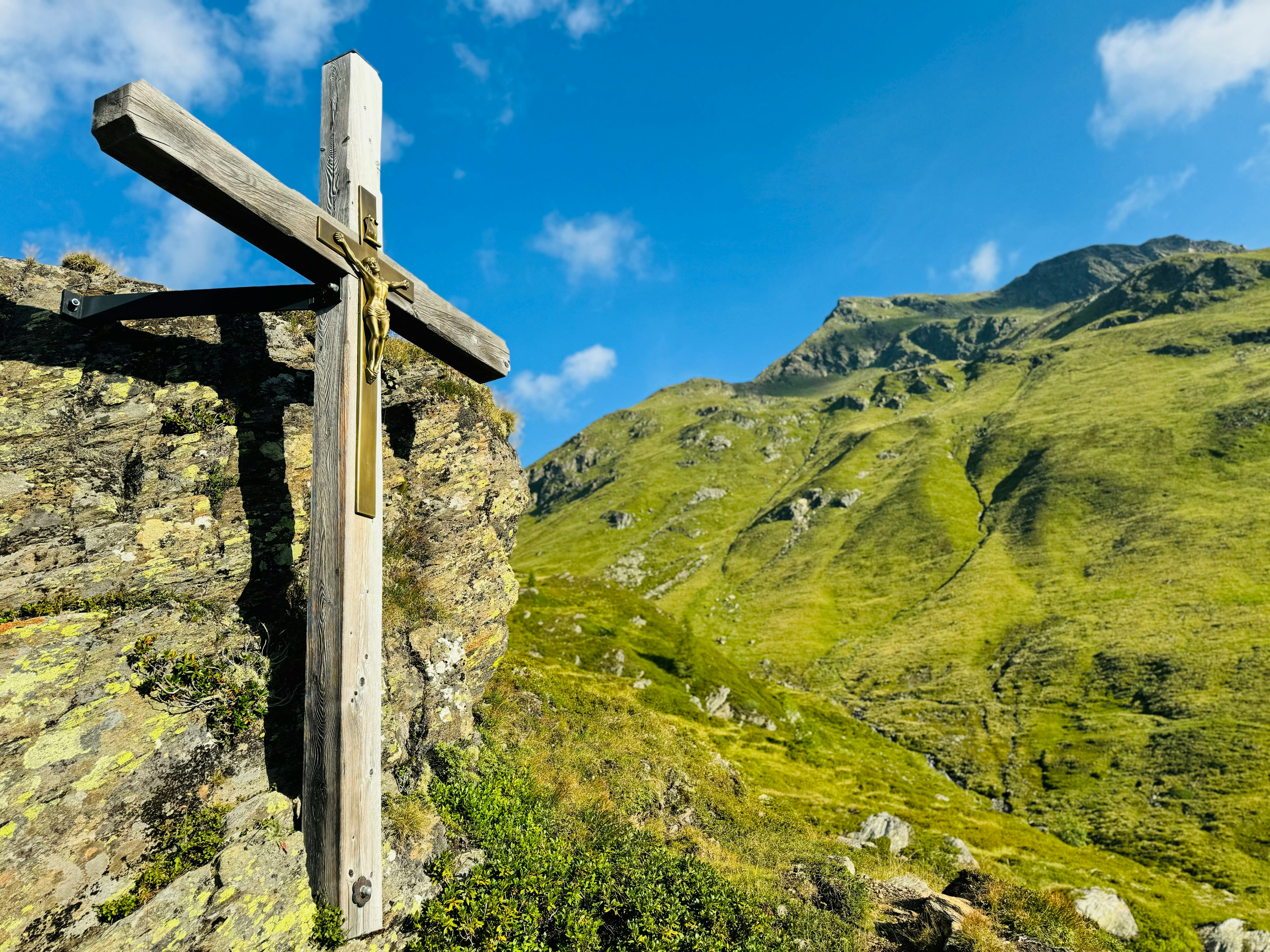 5712x4284 A wooden cross on a hillside with mountains in the background · Free
