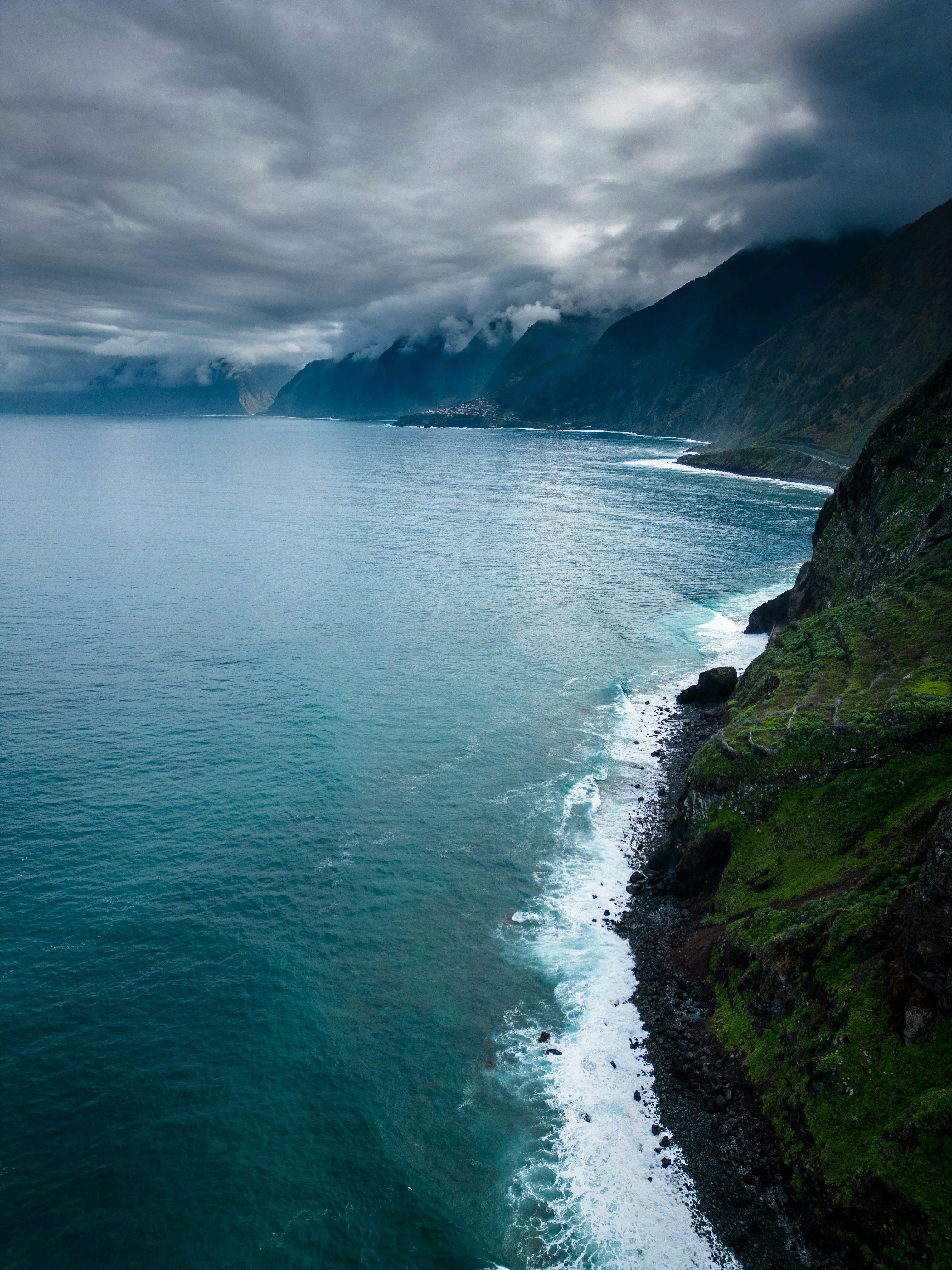 3024x4032 A view of the ocean with a mountain in the background photo