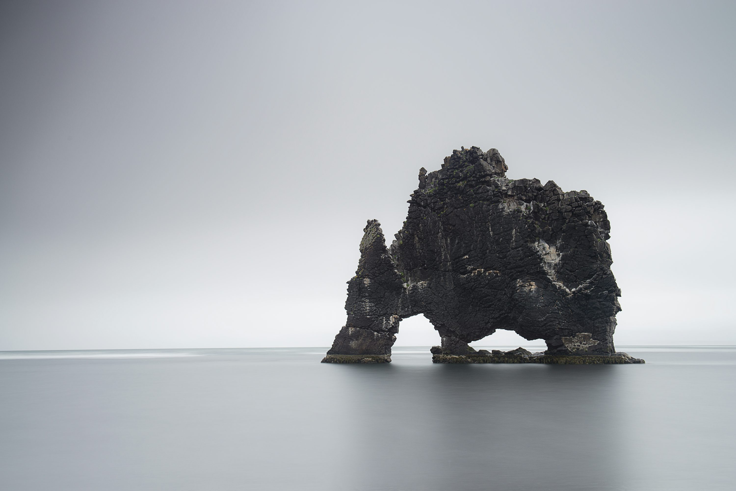 3000x2002 Black rock formation on body of water photo
