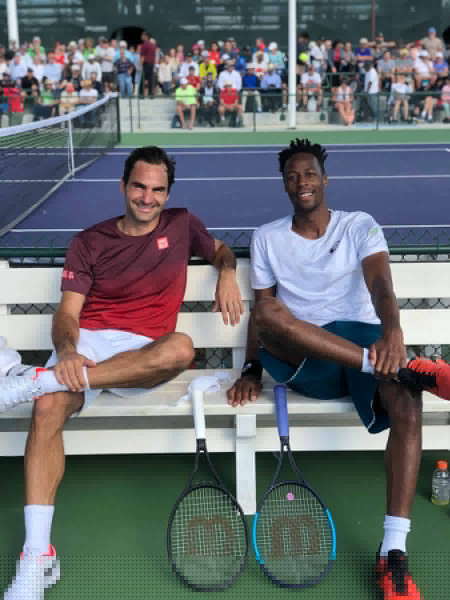 900x1200 Download Gael Monfils competing against Roger Federer in an intense tennis match Wallpaper