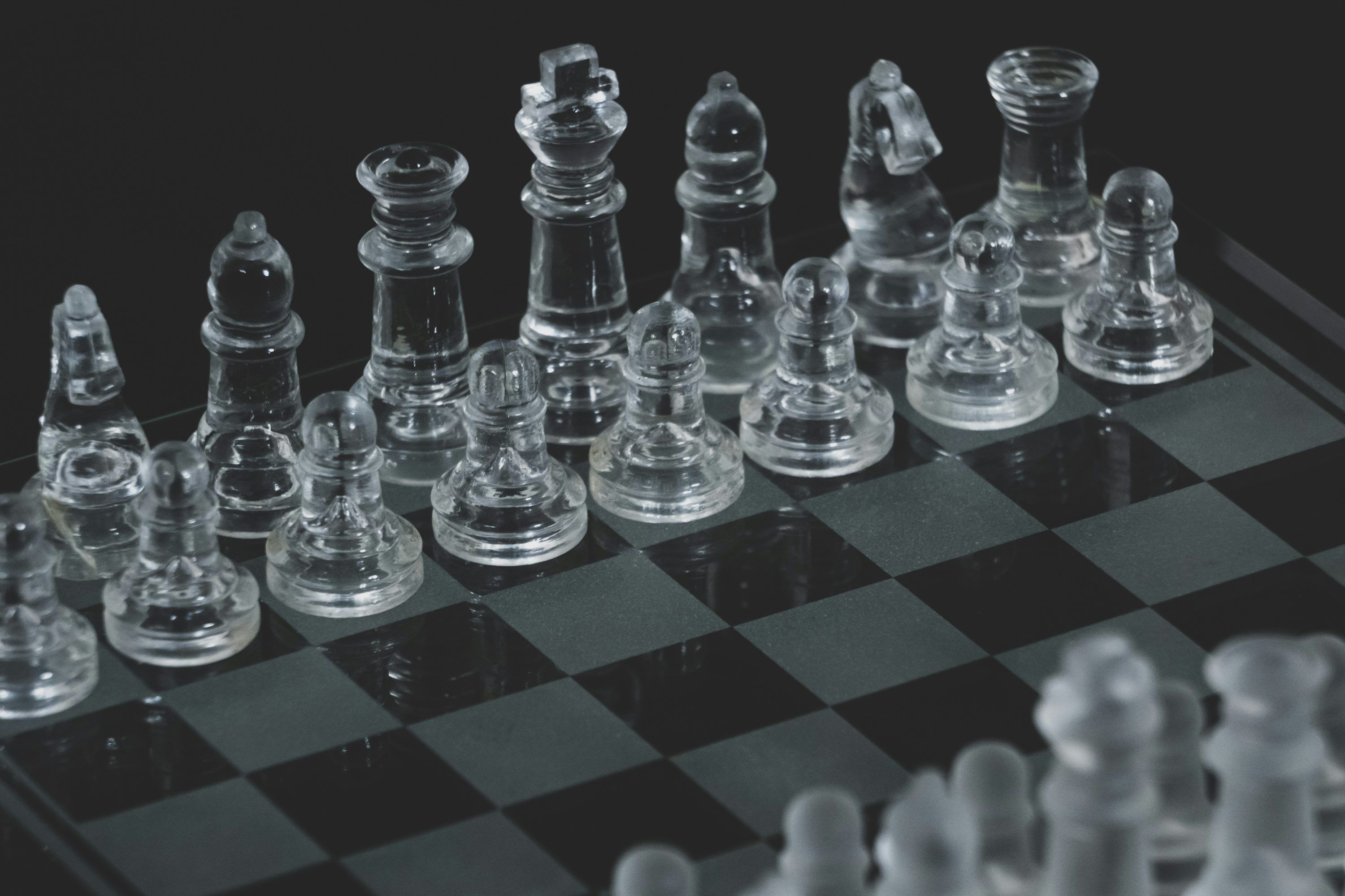 3000x2000 Clear glass chess piece on black and white checkered table photo
