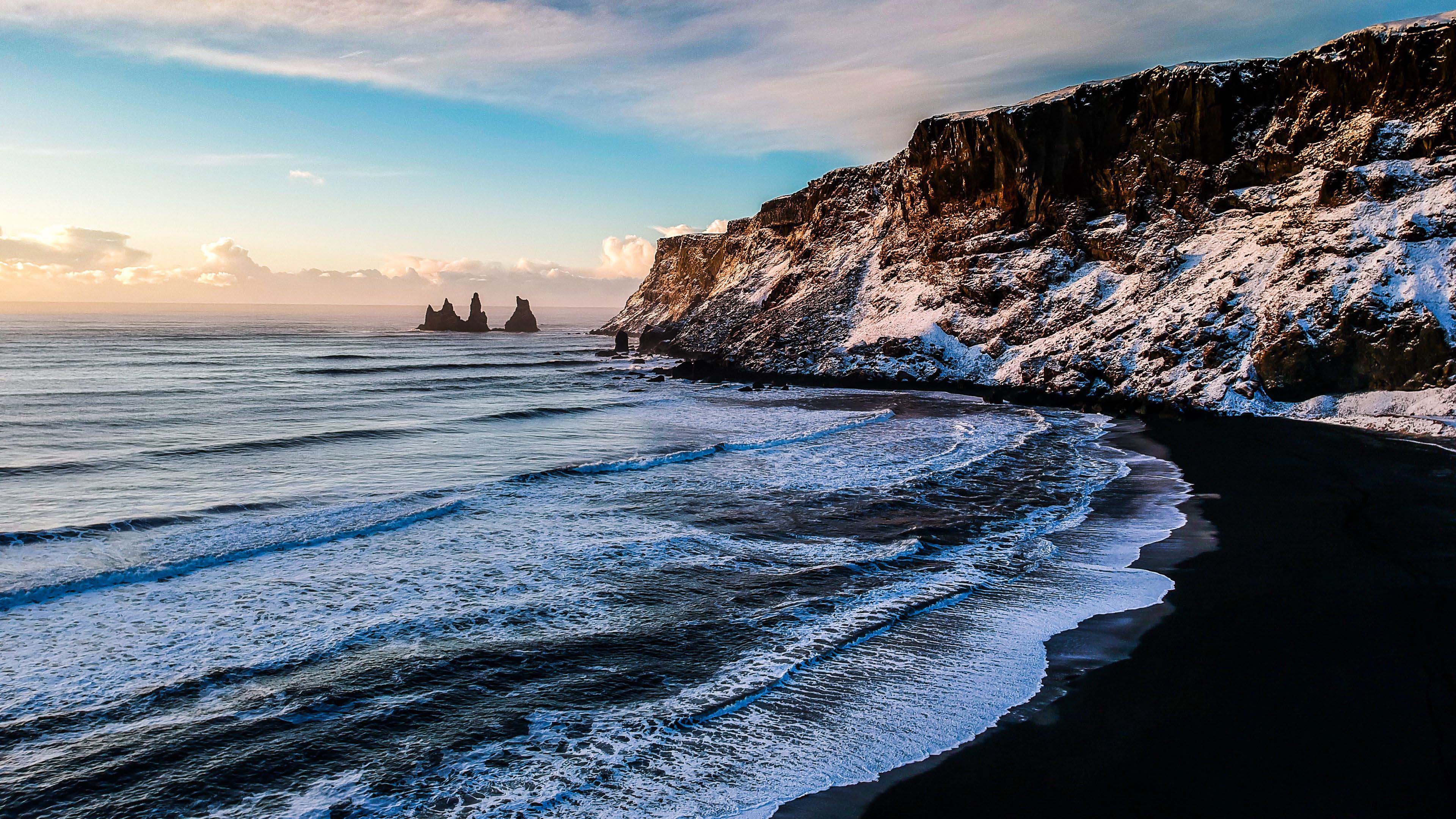 3840x2160 Closeup View Of Ocean Foam Waves Black Beach Sand Rock Mountains With Snow 4K HD Nature Wallpaper