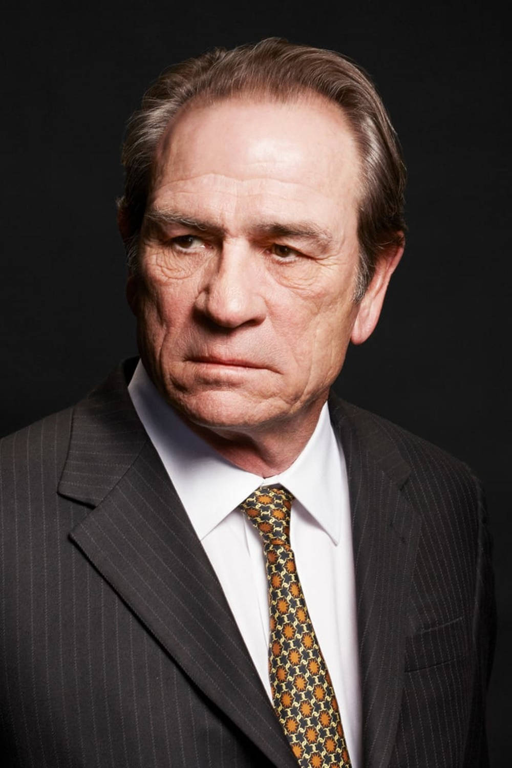 1000x1500 Caption: Portrayal Of Tommy Lee Jones In A Thoughtful Indoor Headshot Wallpaper