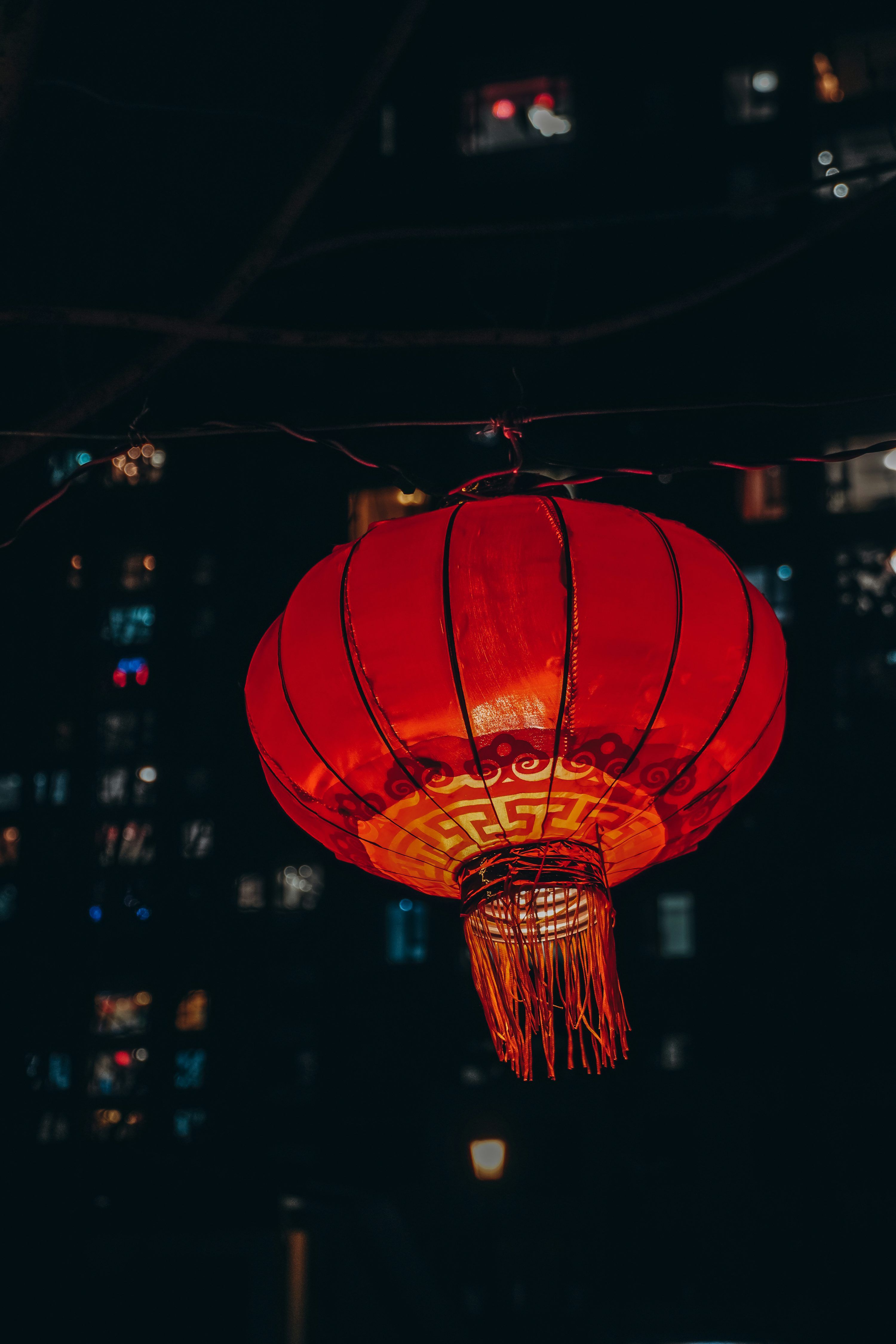 3000x4500 A red lantern hanging from a wire in the dark photo