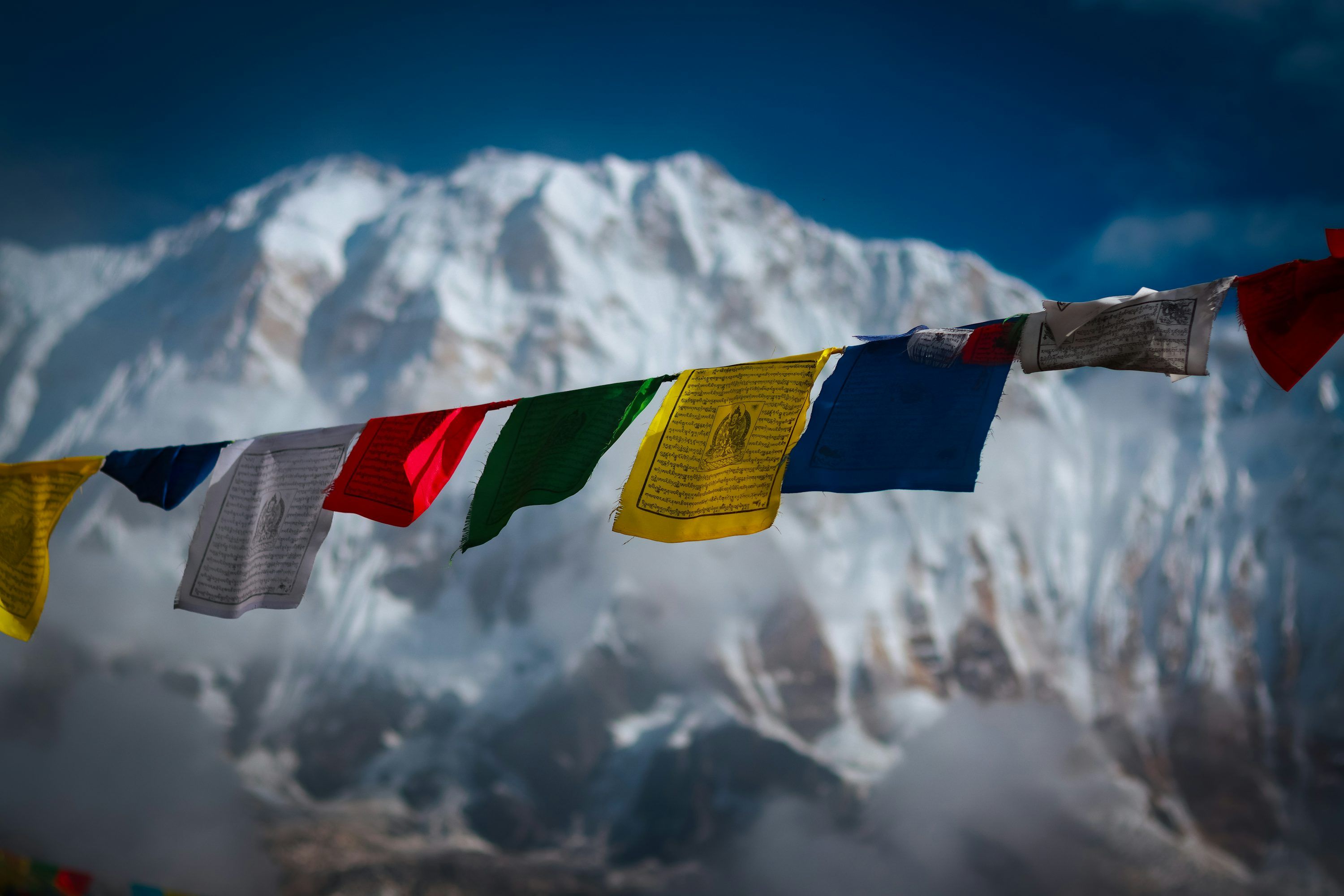 3000x2000 Prayer flags flutter against a snowy mountain backdrop. photo