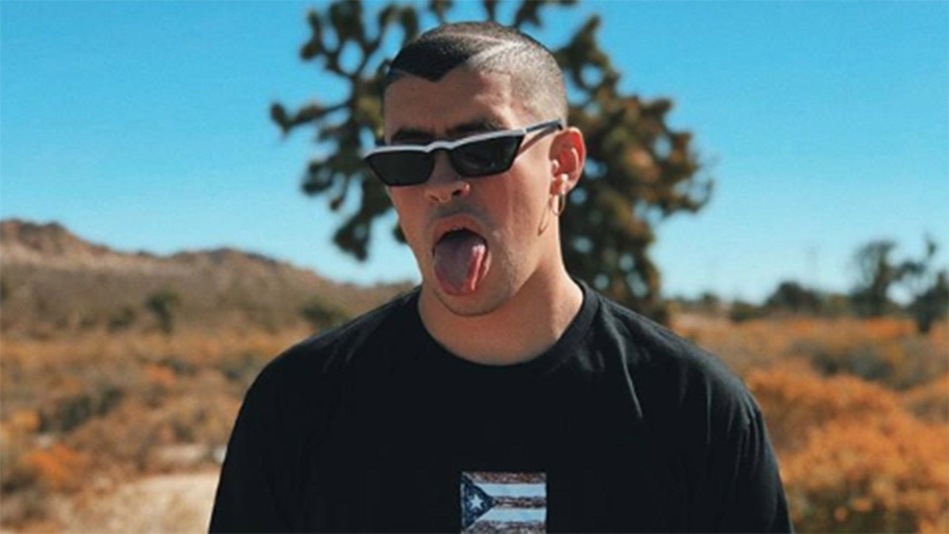 1920x1080 Bad Bunny Aesthetic Is Wearing Black Tshirt Standing In Blur Background With Tongue Out HD Music Wallpaper
