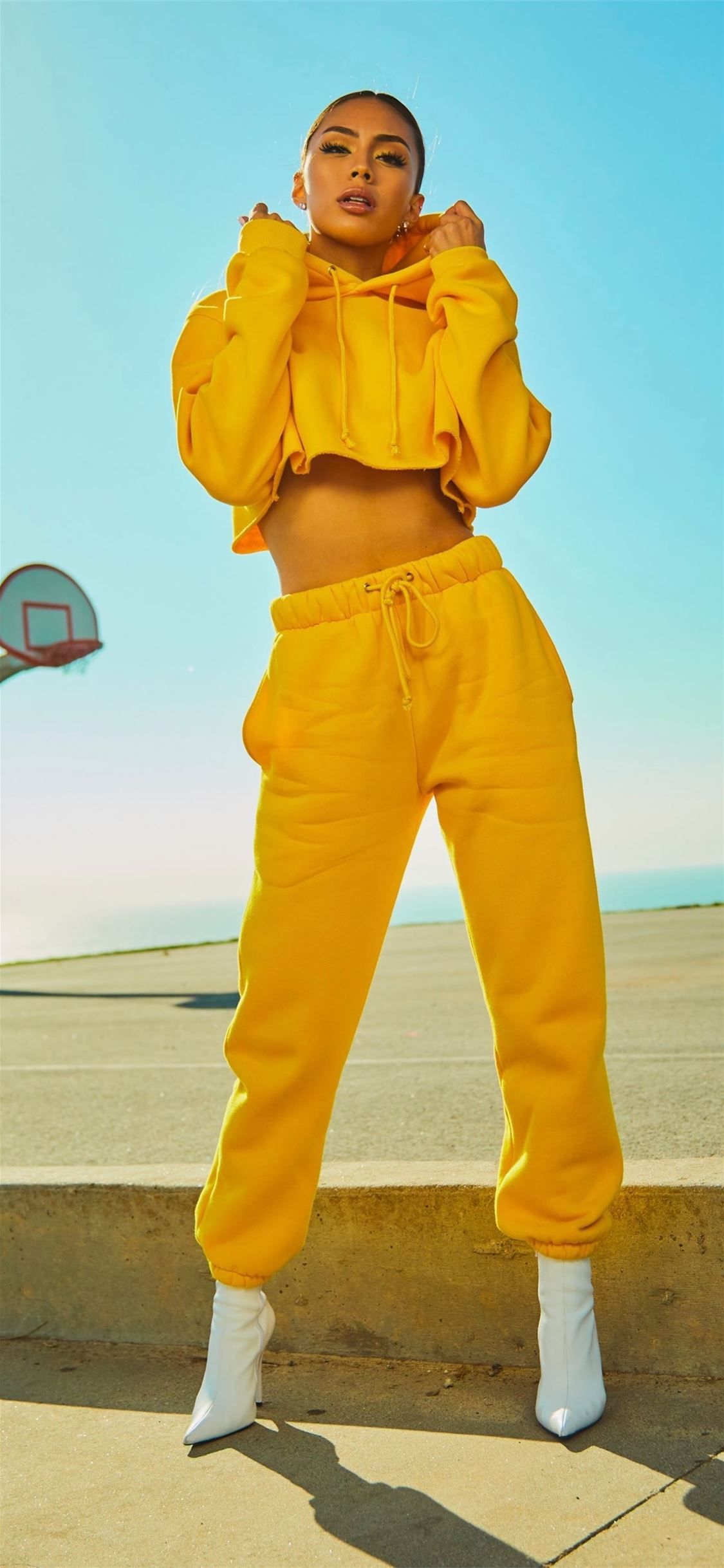 1125x2436 woman in yellow tracksuit standing on basketball c. iPhone X Wallpaper Free Download