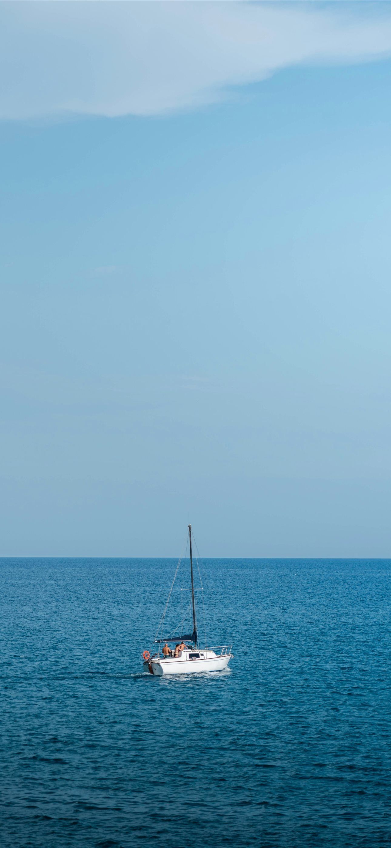 1290x2796 A sailboat floating in the middle of the ocean iPhone Wallpaper Free Download