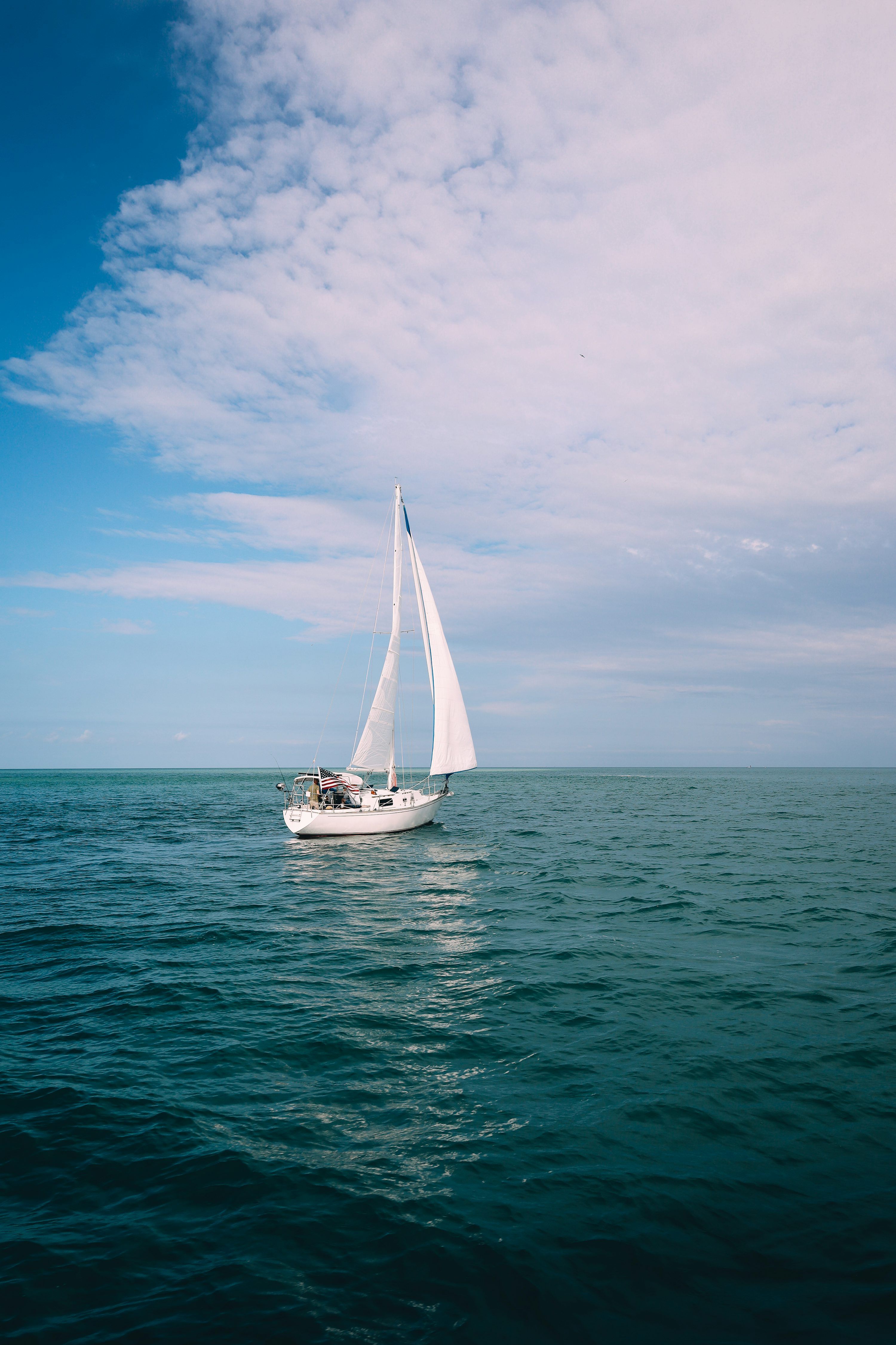 3000x4500 A sailboat sailing on the ocean under a cloudy blue sky photo