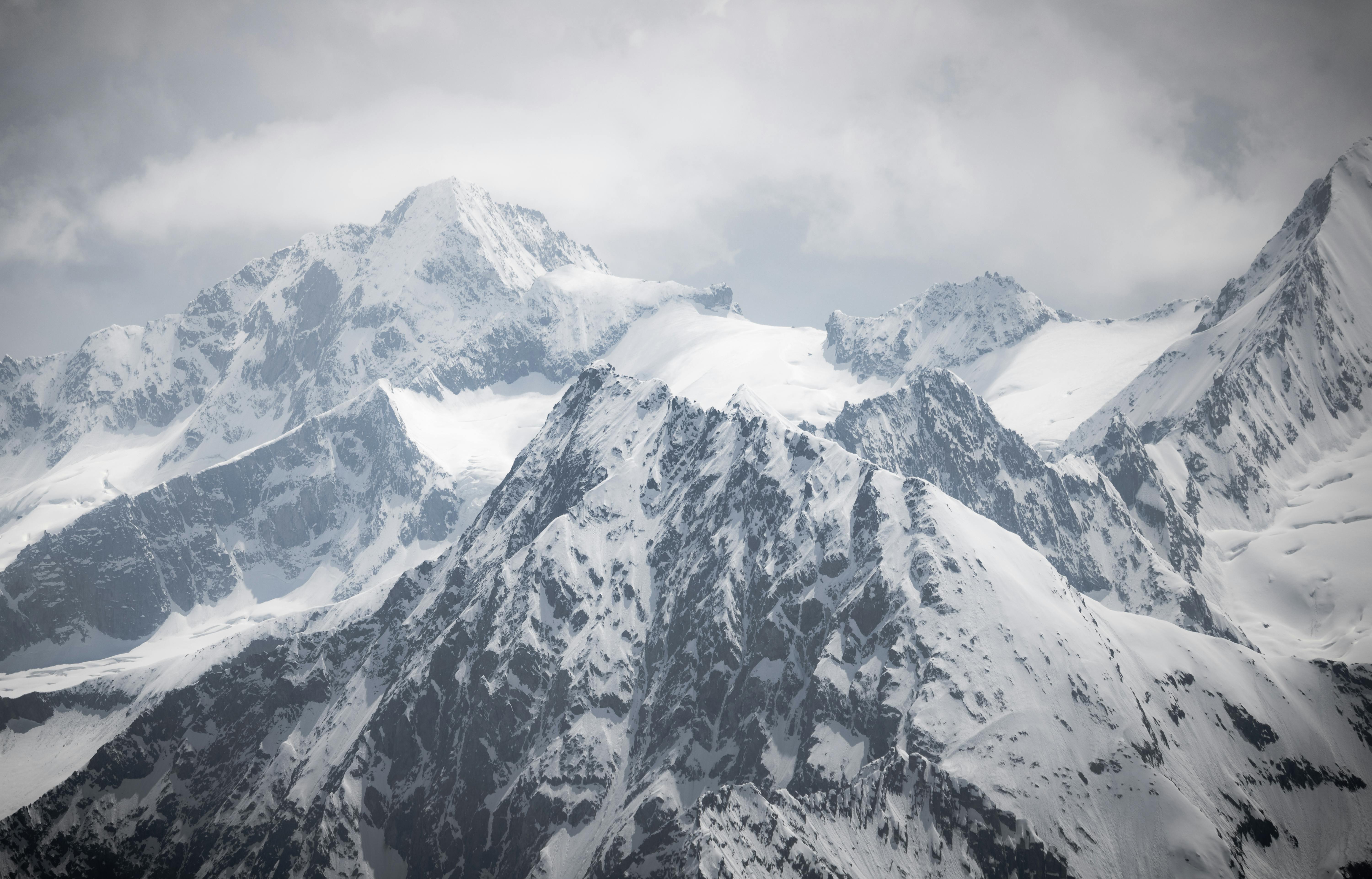 6000x3845 A photo of a snowy mountain range with clouds · Free