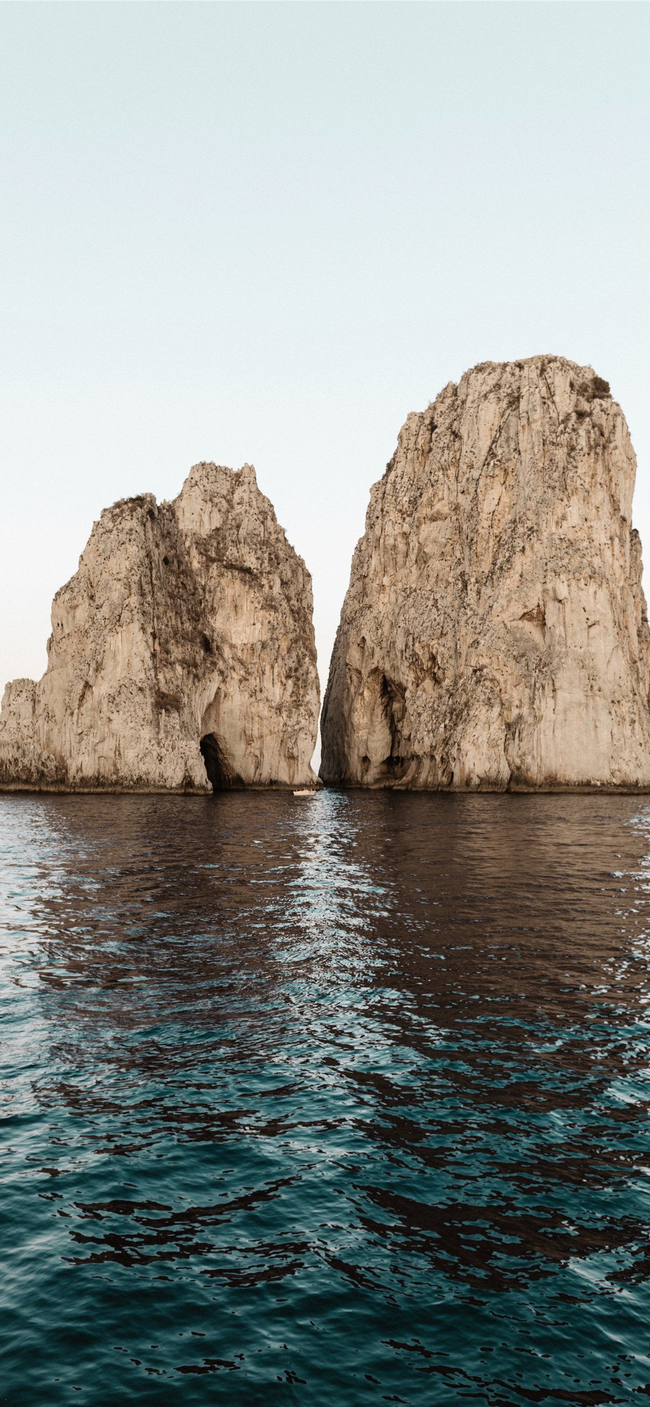 1284x2778 two beige rock formations on body of water iPhone Wallpaper Free Download