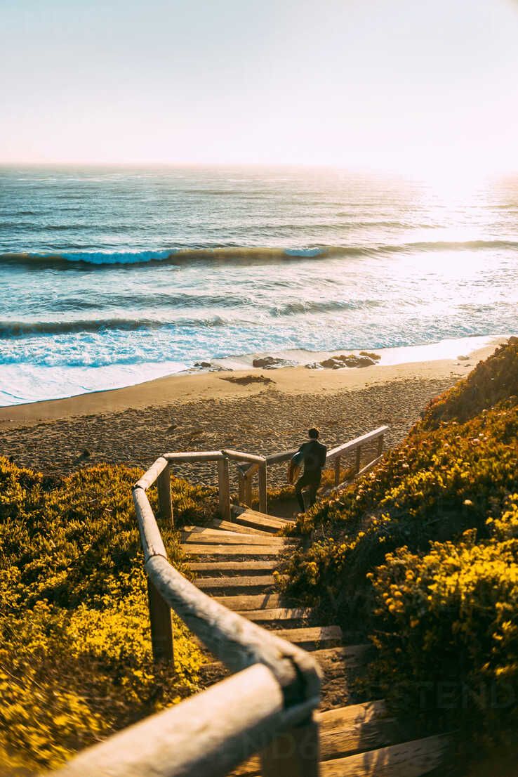 738x1106 Surfer with surfboard on beach, Morro Bay, California, United States