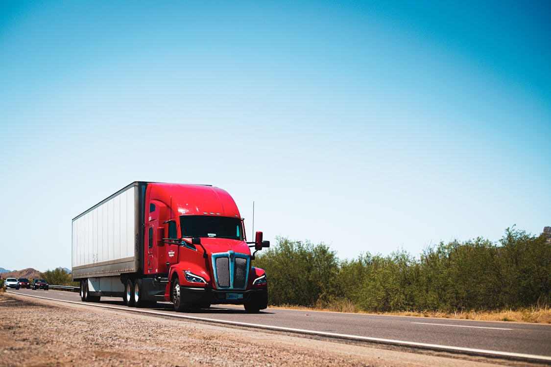 1125x750 Kenworth T680 Semi Truck Driving Down The Road · Free