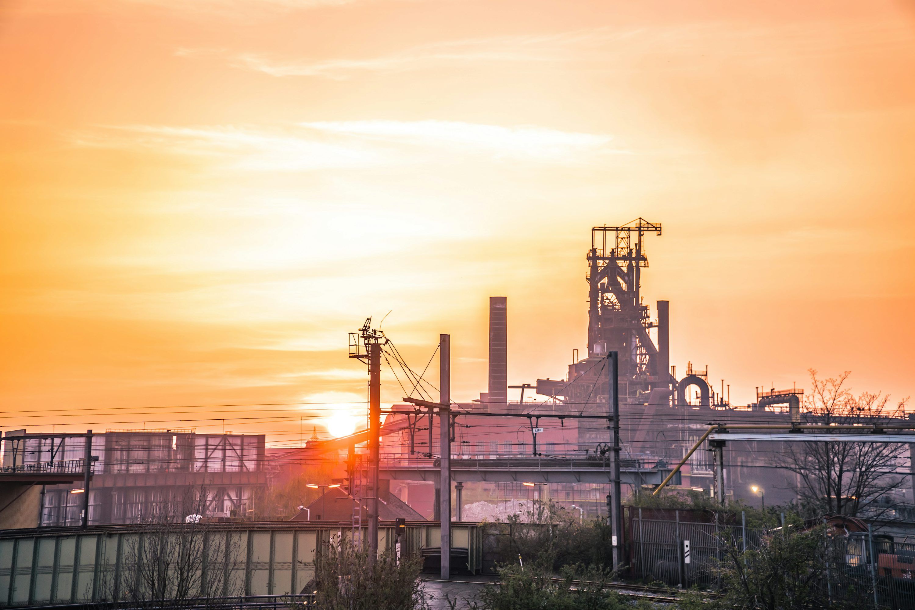 3000x2000 Industrial complex silhouetted against a bright sunset photo