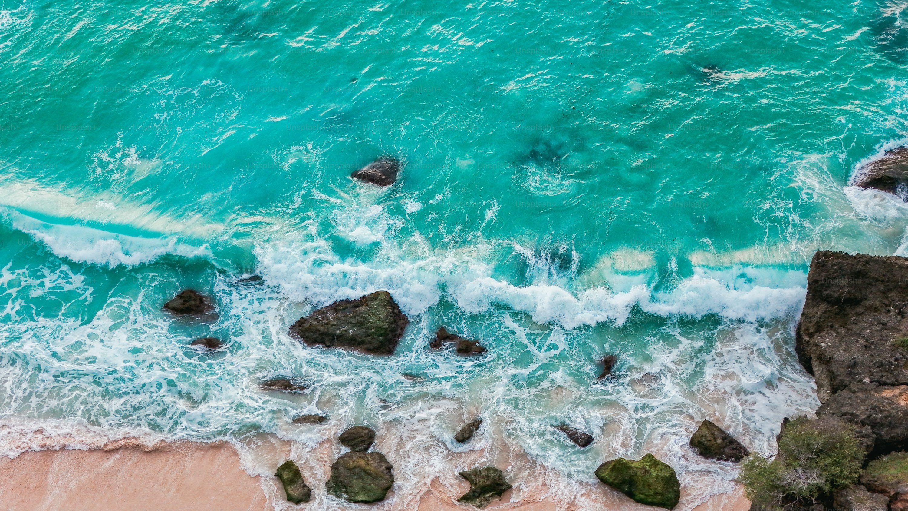 3000x1687 Aerial view of turquoise waves washing over white sand on a tropical coral beach photo