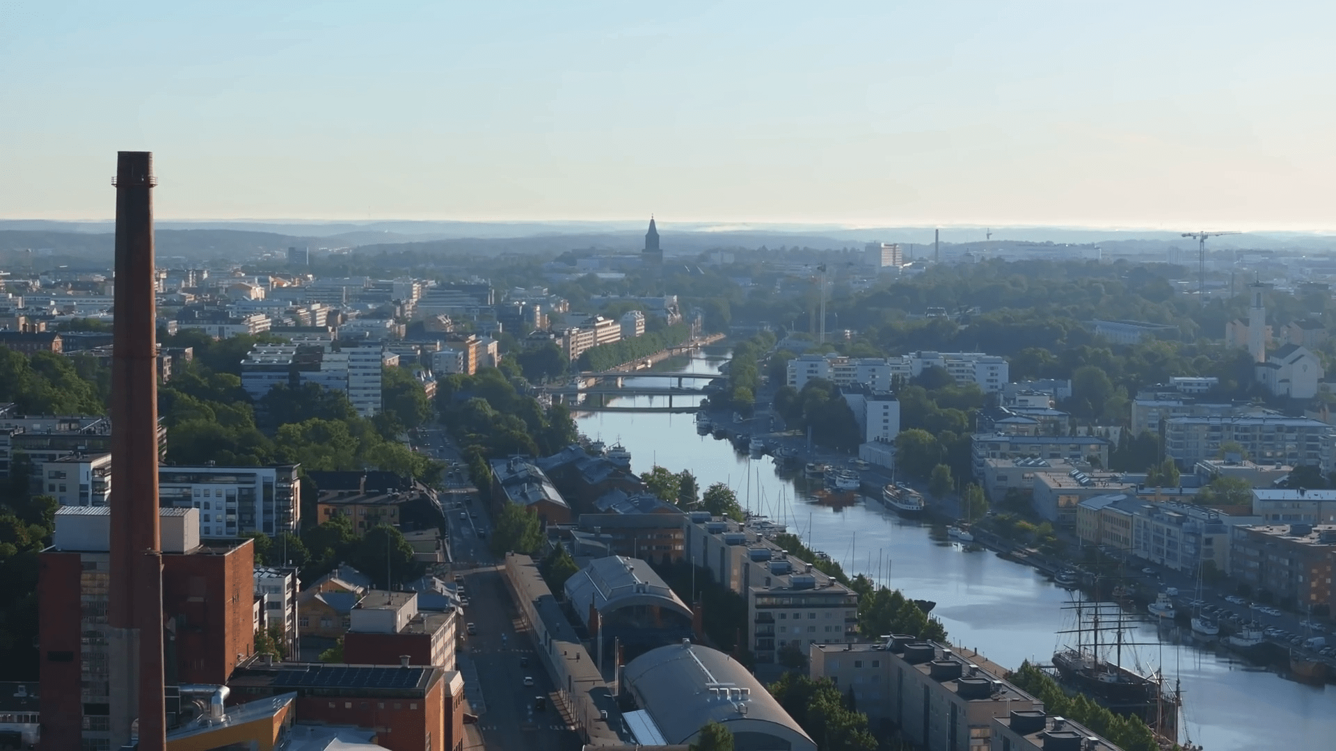1920x1080 Aerial view of Turku, Finland showcasing the Aura River flowingy center and a prominent industrial chimney