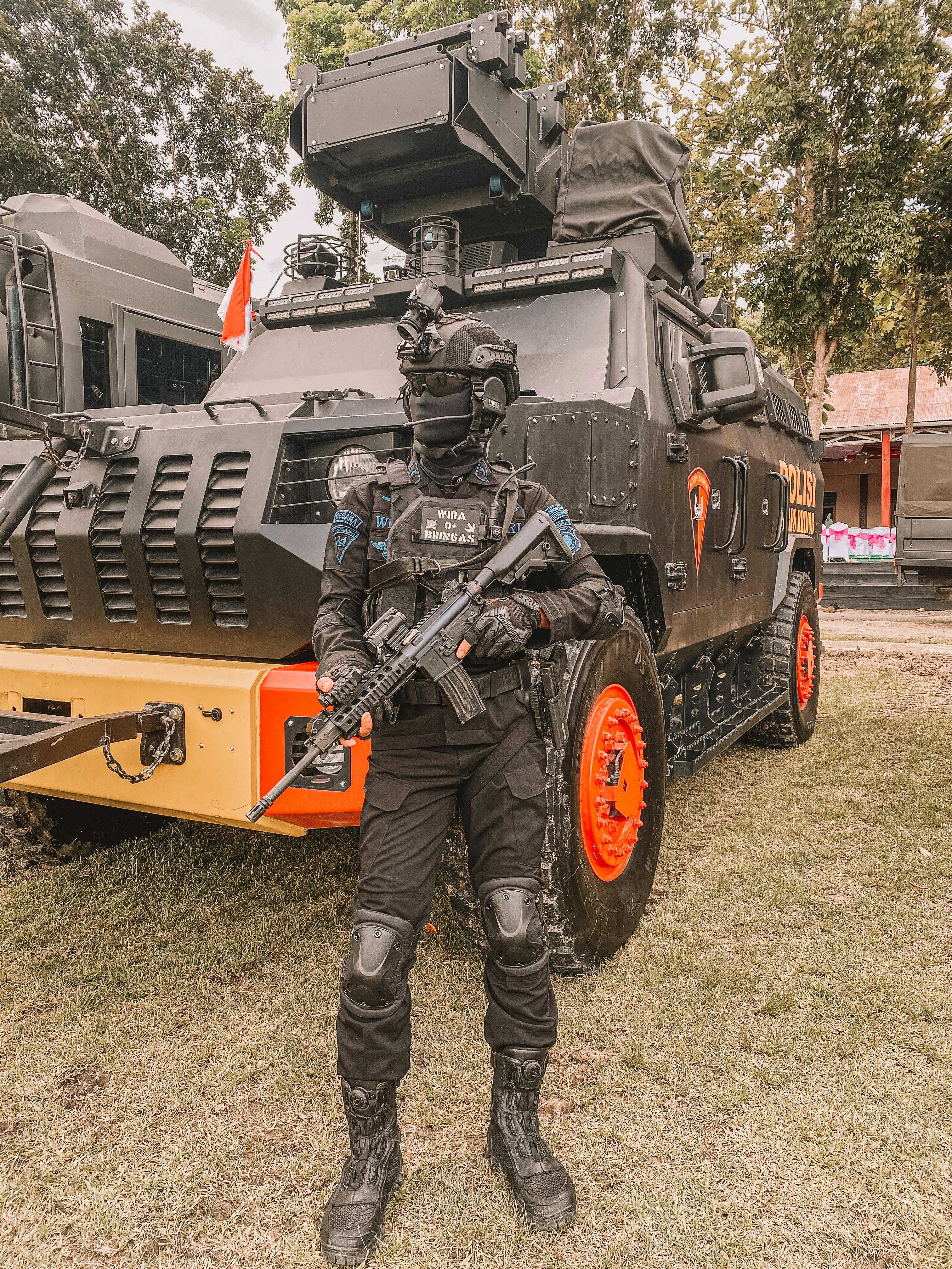 3024x4032 A Person in Military Uniform Holding a Rifle while Standing Near Army Truck · Free