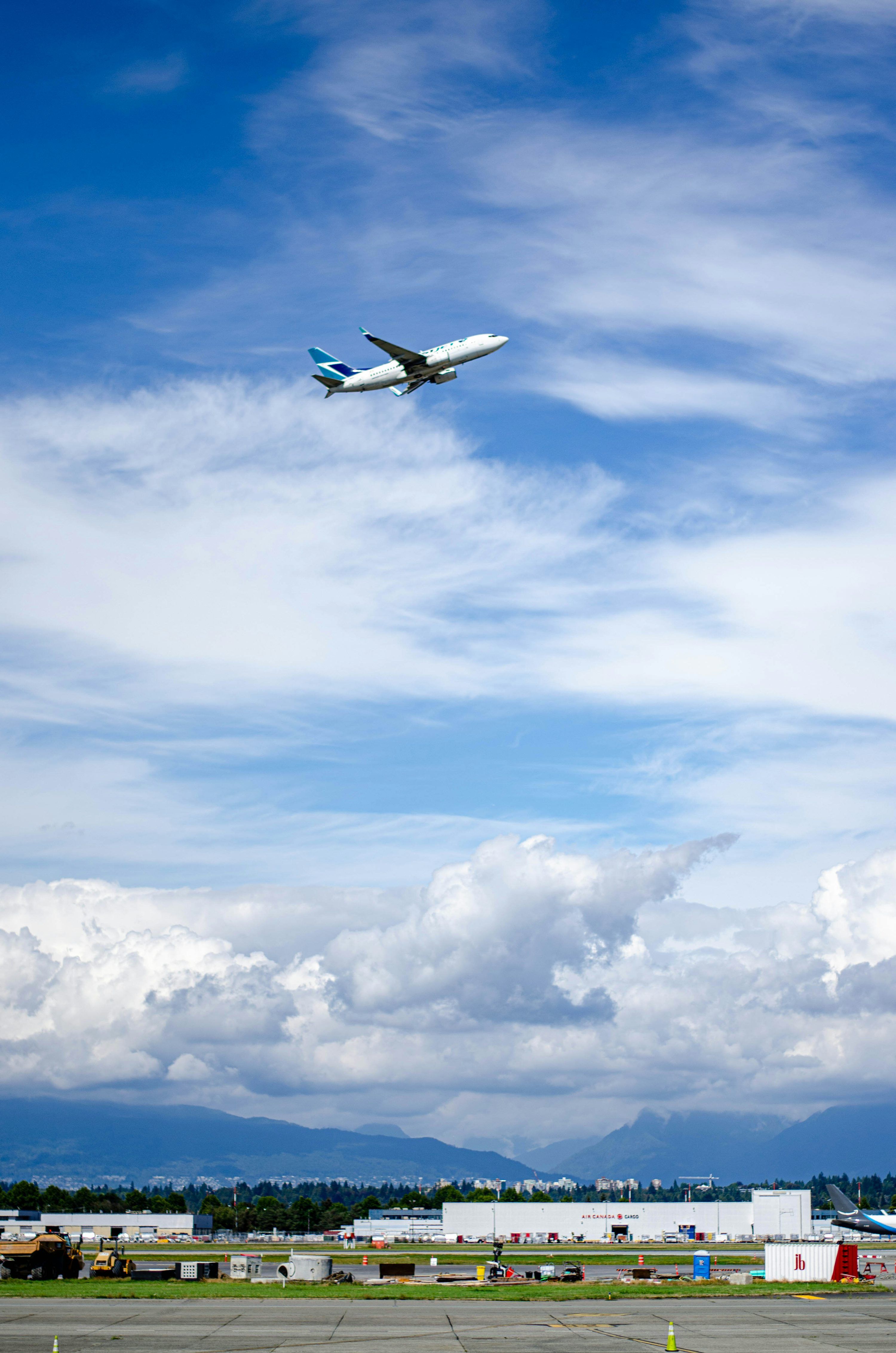 3000x4529 An airplane flying in the sky over a runway photo