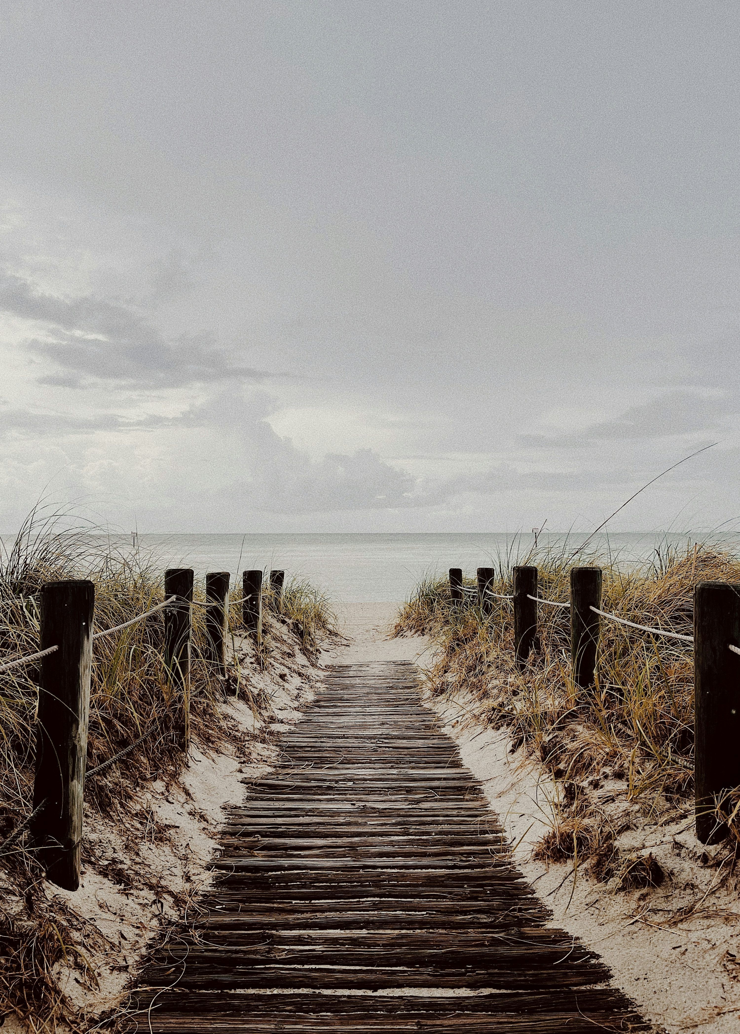 3000x4191 A wooden path leading to the beach on a cloudy day photo