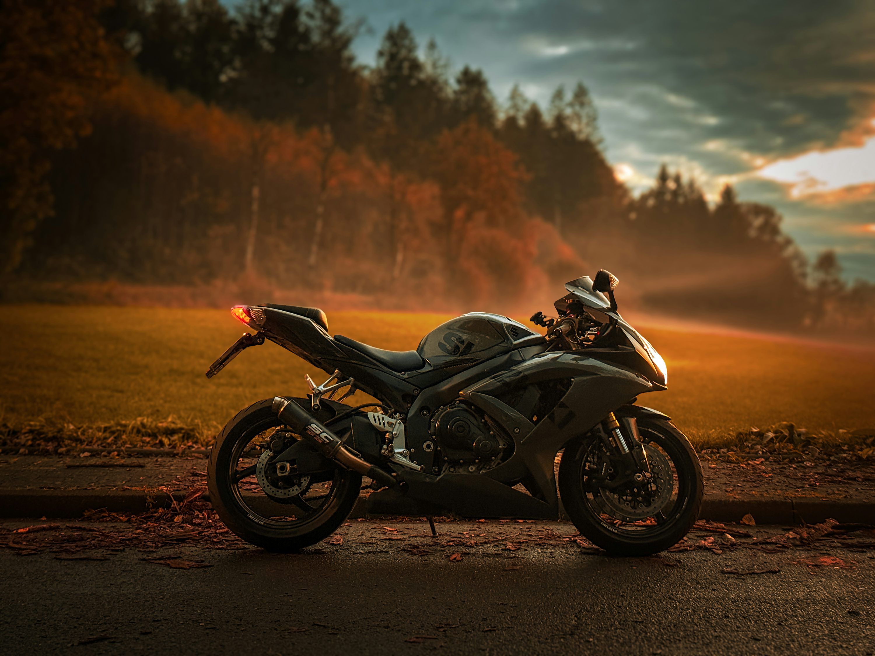 3000x2250 A sleek motorcycle sits in a vibrant sunset landscape. photo