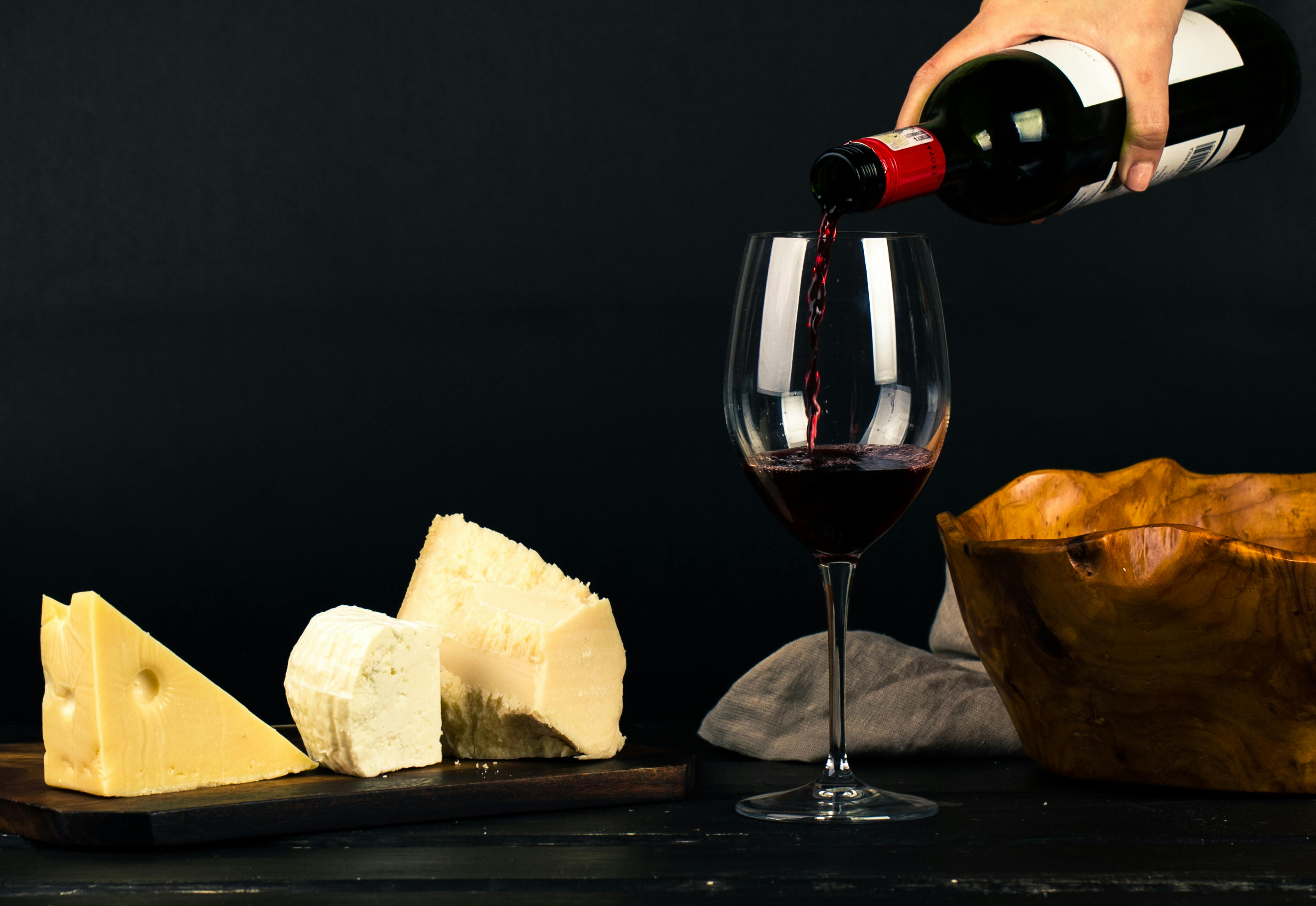 5022x3456 Photo of Person Pouring Wine into Glass besides Some Cheese Pairings · Free