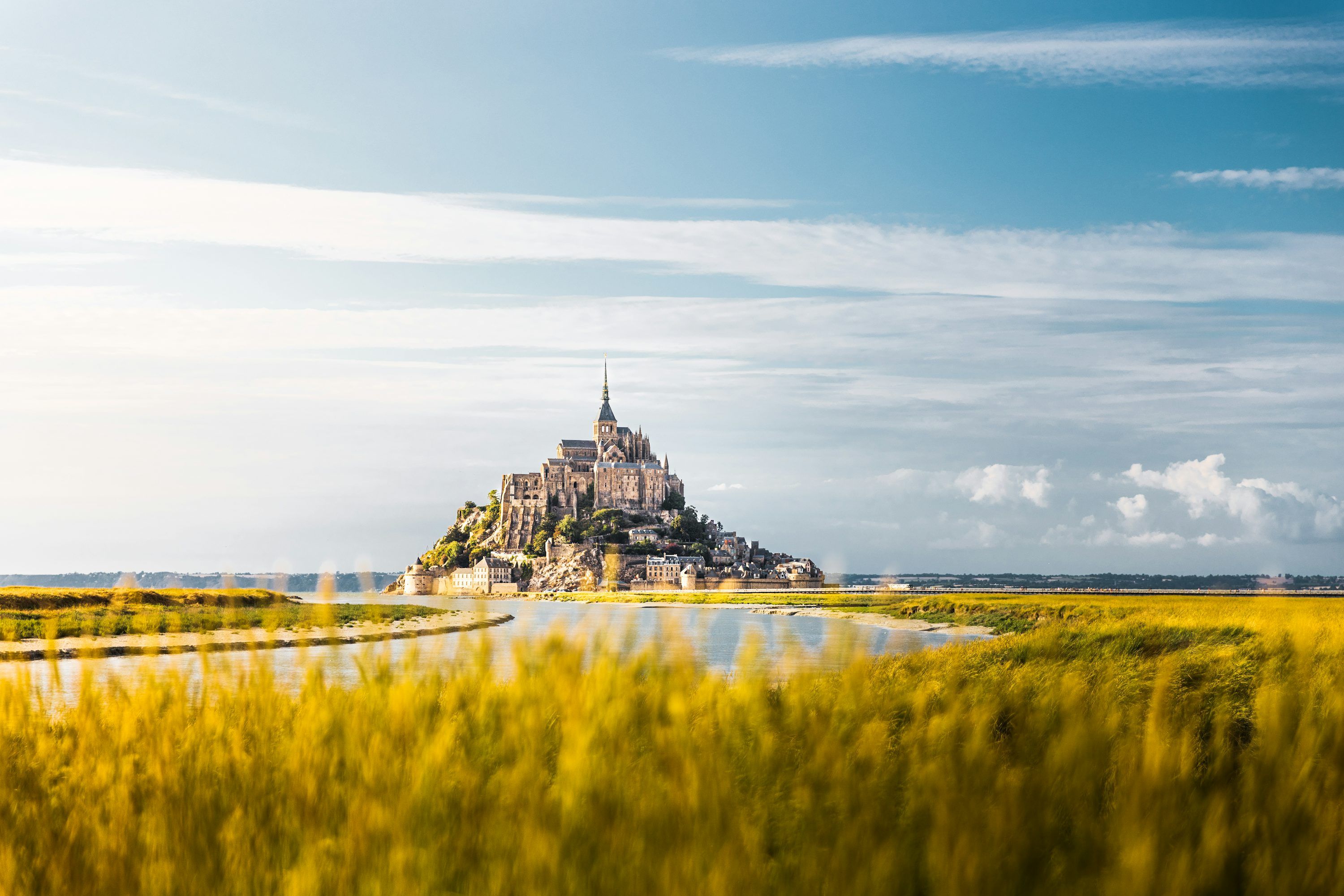 3000x2001 A Castle On A Hill By A Body Of Water With Mont Saint Michel In The Background Photo