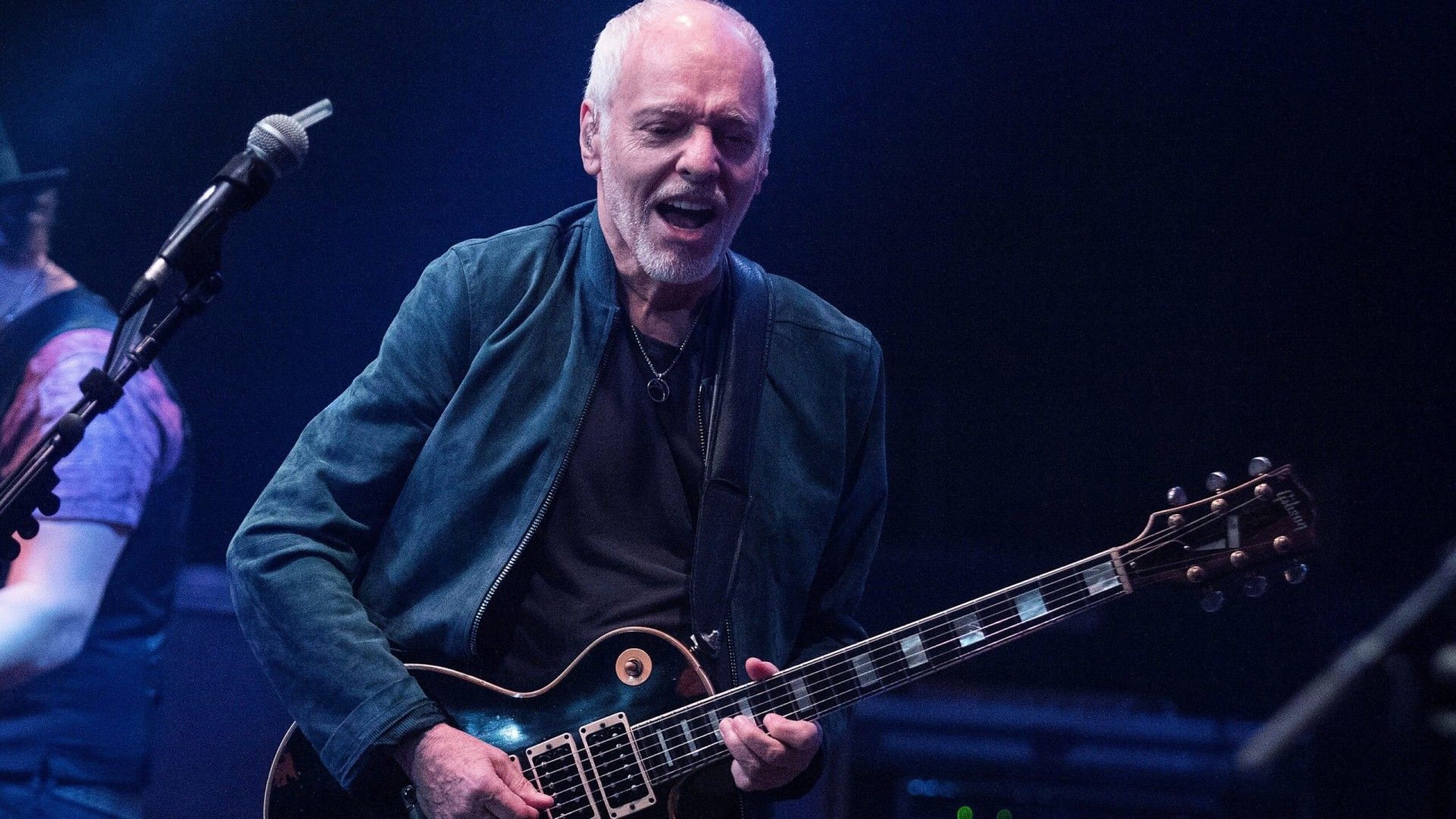 1920x1080 Peter Frampton With Guitar In Black Background Is Wearing Black Overcoat HD Peter Frampton Wallpaper
