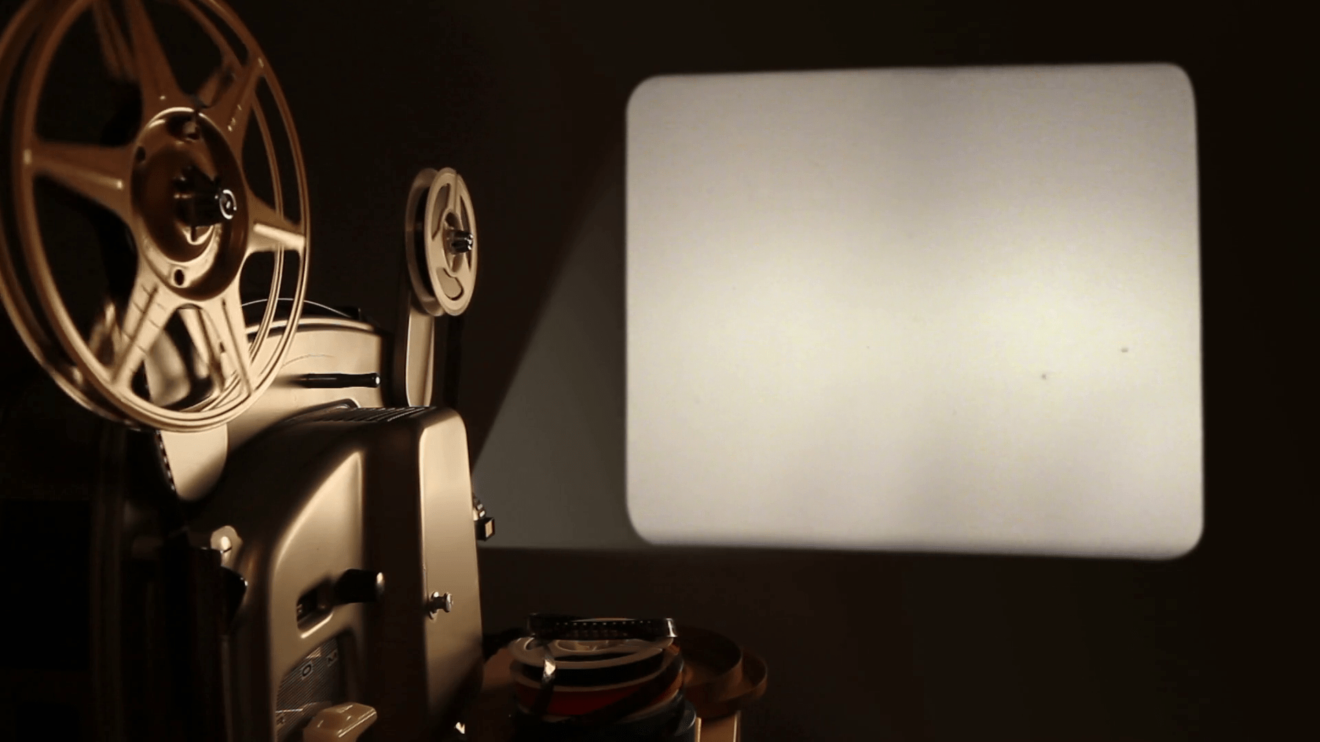 1920x1080 An antique 8mm film projector is turned on in a dark room, and projects a blank movie with a dust and hair texture, lifted from real 8mm film. Includes projector audio