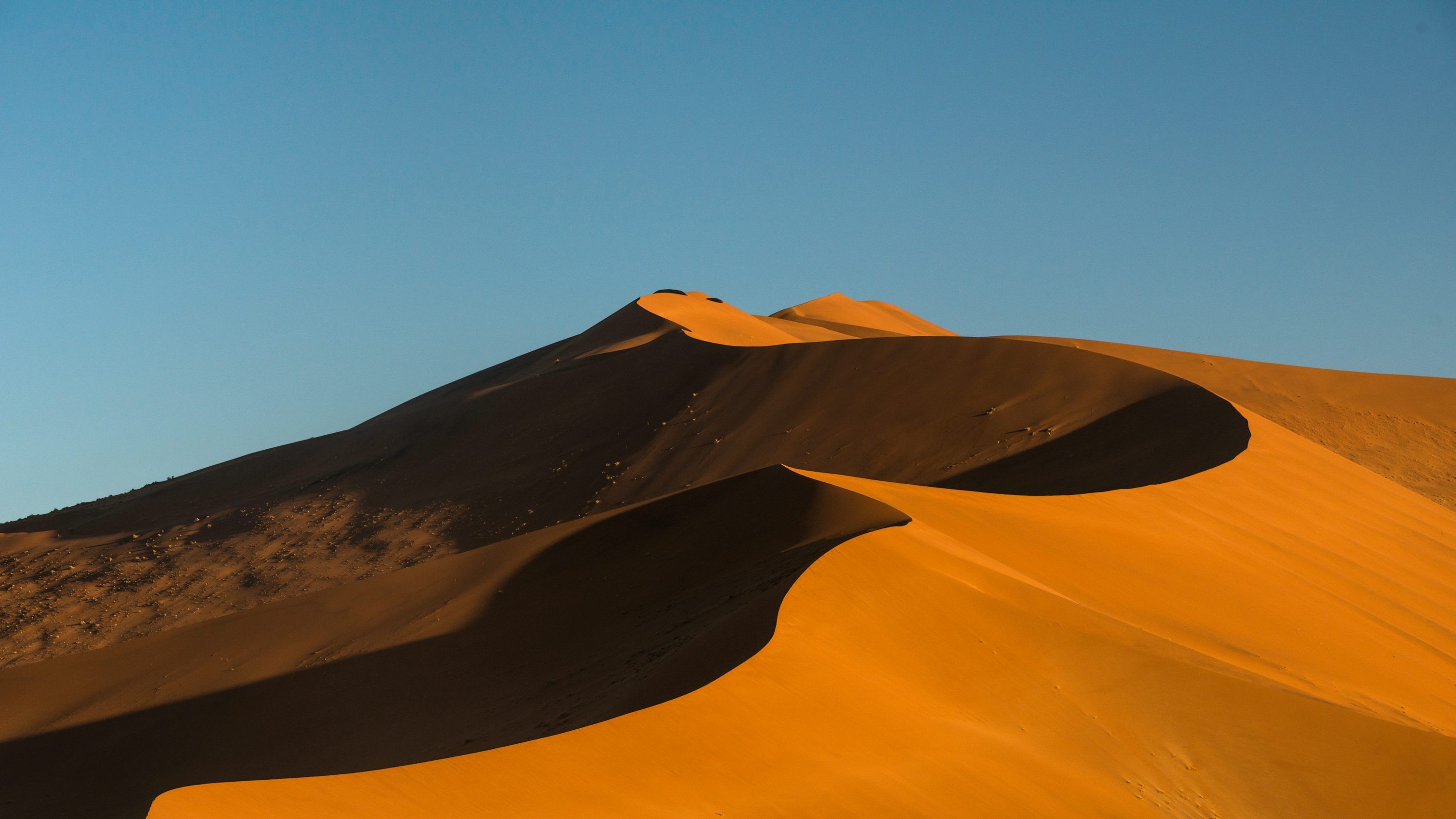 3000x1688 A group of sand dunes with a blue sky in the background photo