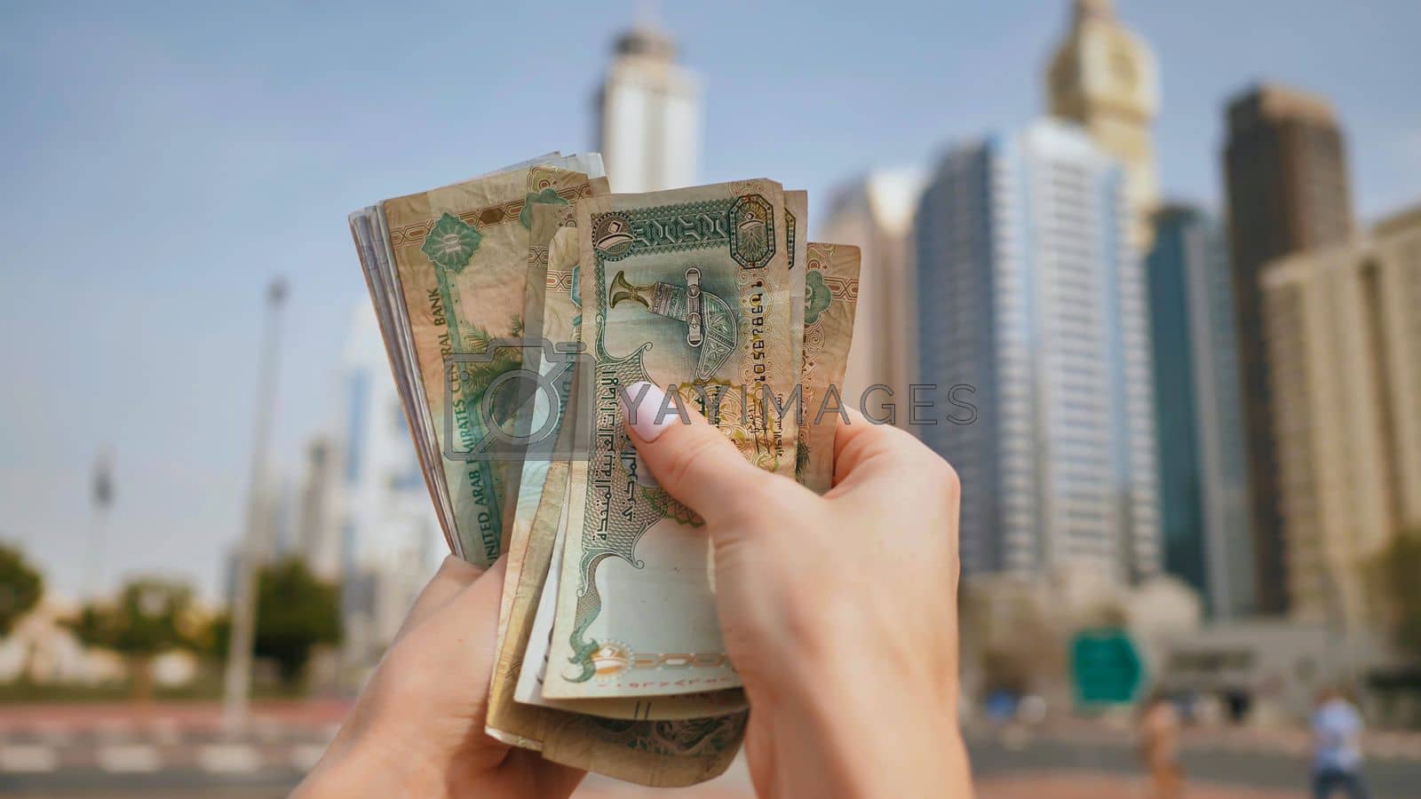 1600x900 Hands of a girl holding money of the United Arab Emirates on the background of Dubai skyscrapers. by DovidPro Vectors & Illustrations with Unlimited Downloads