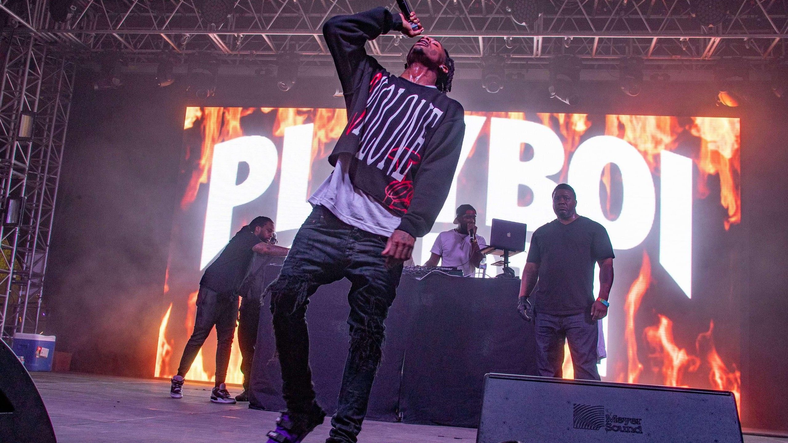 2560x1440 playboi carti is singing on stage wearing black and white tshirt and jeans with band background HD music Wallpaper