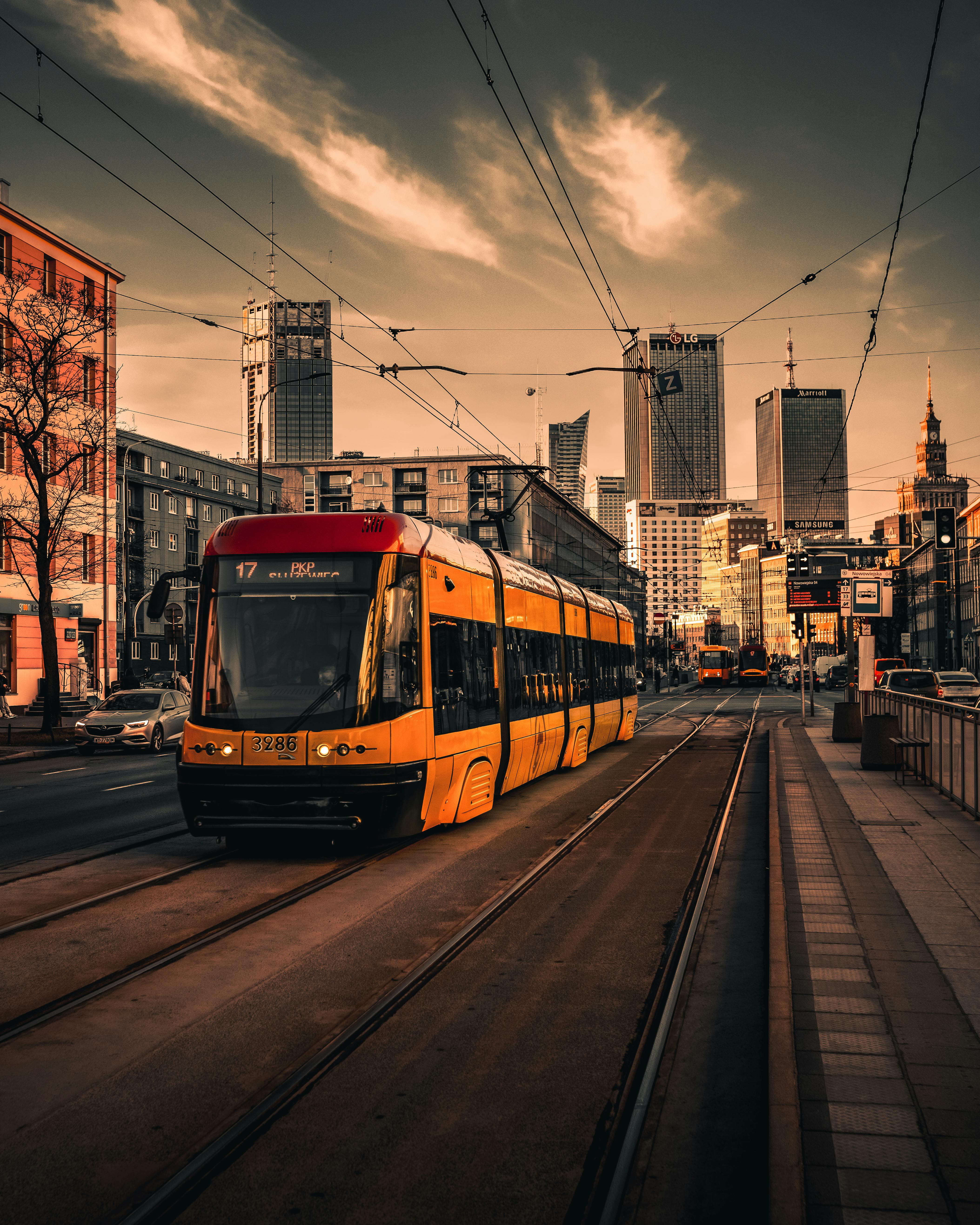 4213x5266 A red train on a track next to a city street · Free