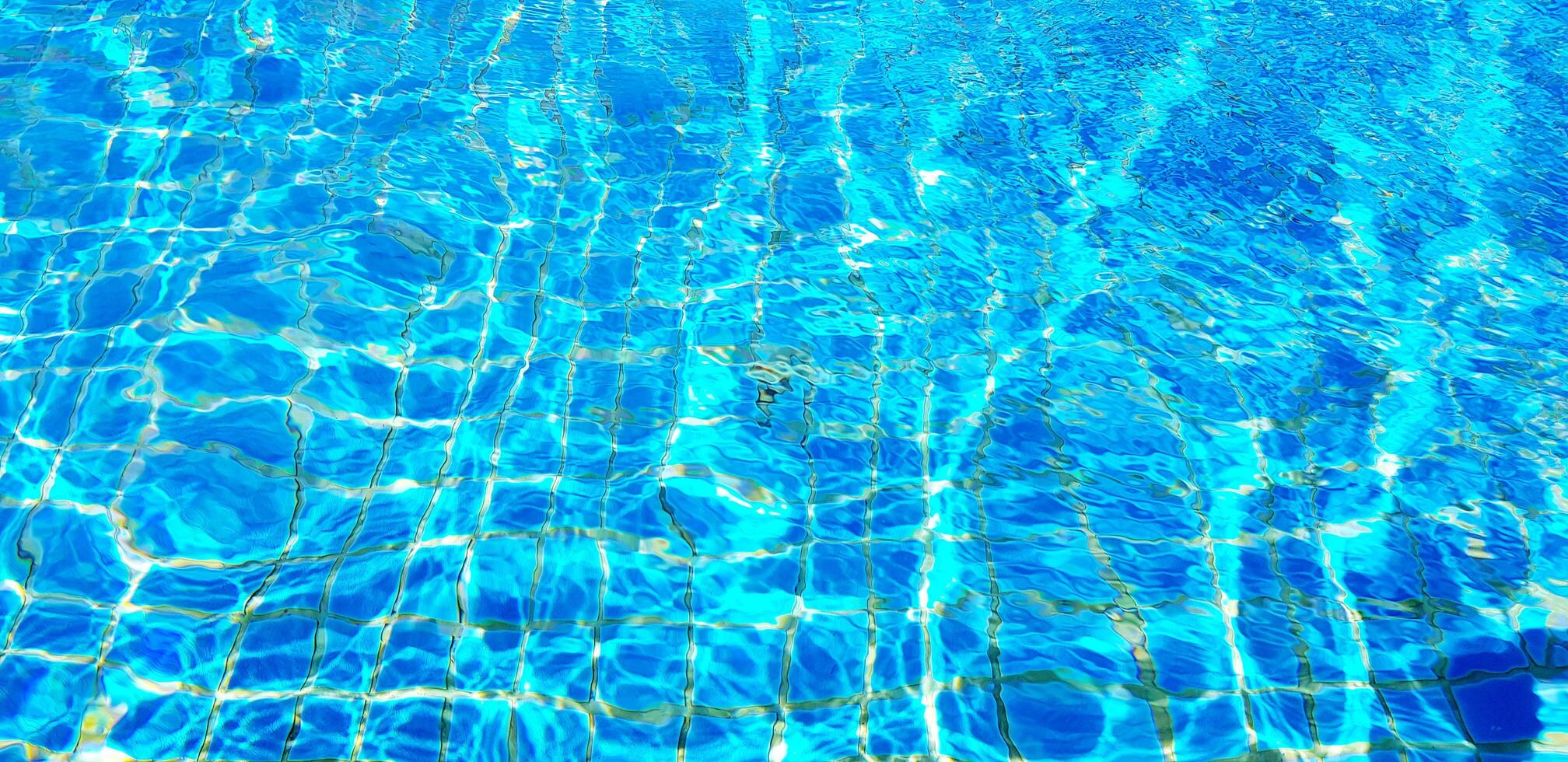 2016x980 Wave or ripple water in swimming pool with sunlight reflection for background. Art or Abstract and Wallpaper concept