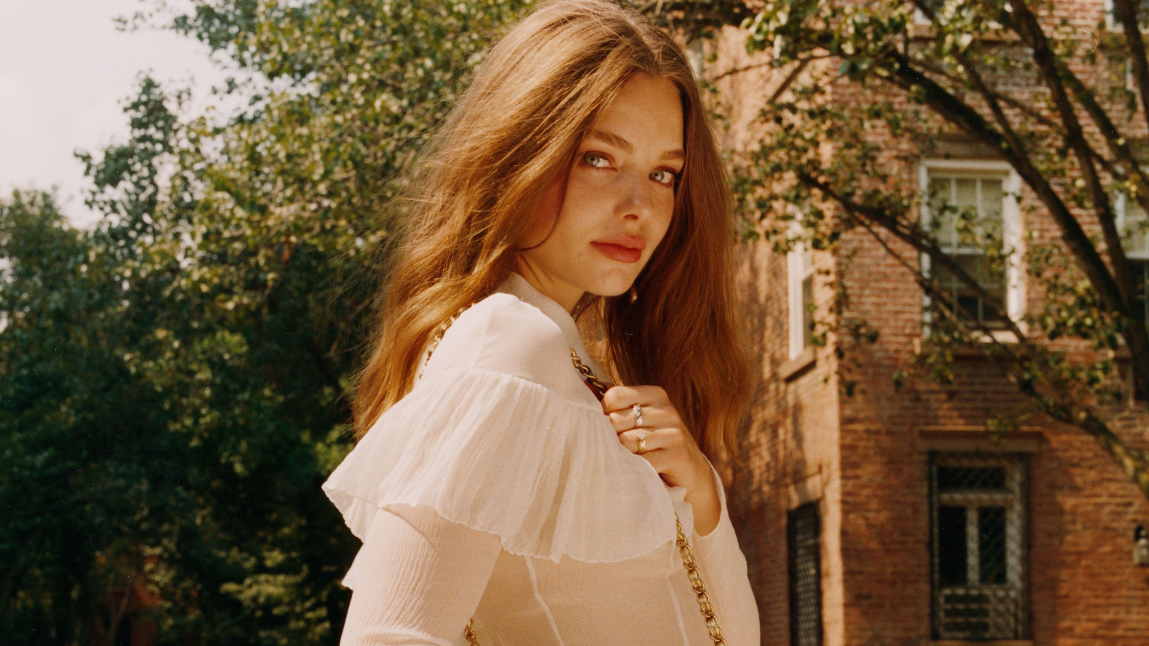 3840x2160 Girl Model Kristine Froseth Is Wearing White Dress Standing In Green Trees Background 4K 5K HD Girls Wallpaper