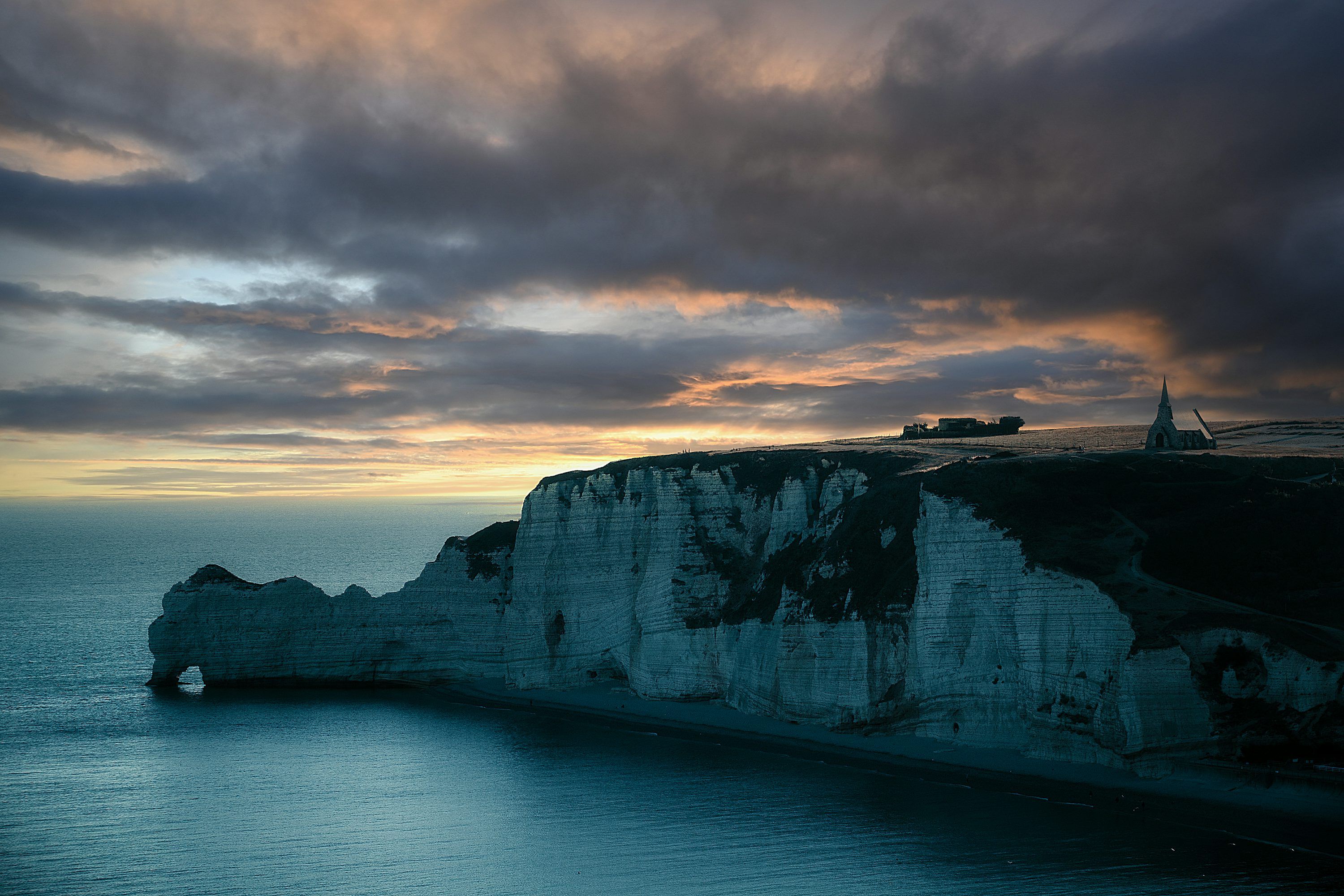 3000x2000 A rocky cliff with a body of water below with White Cliffs of Dover in the background photo