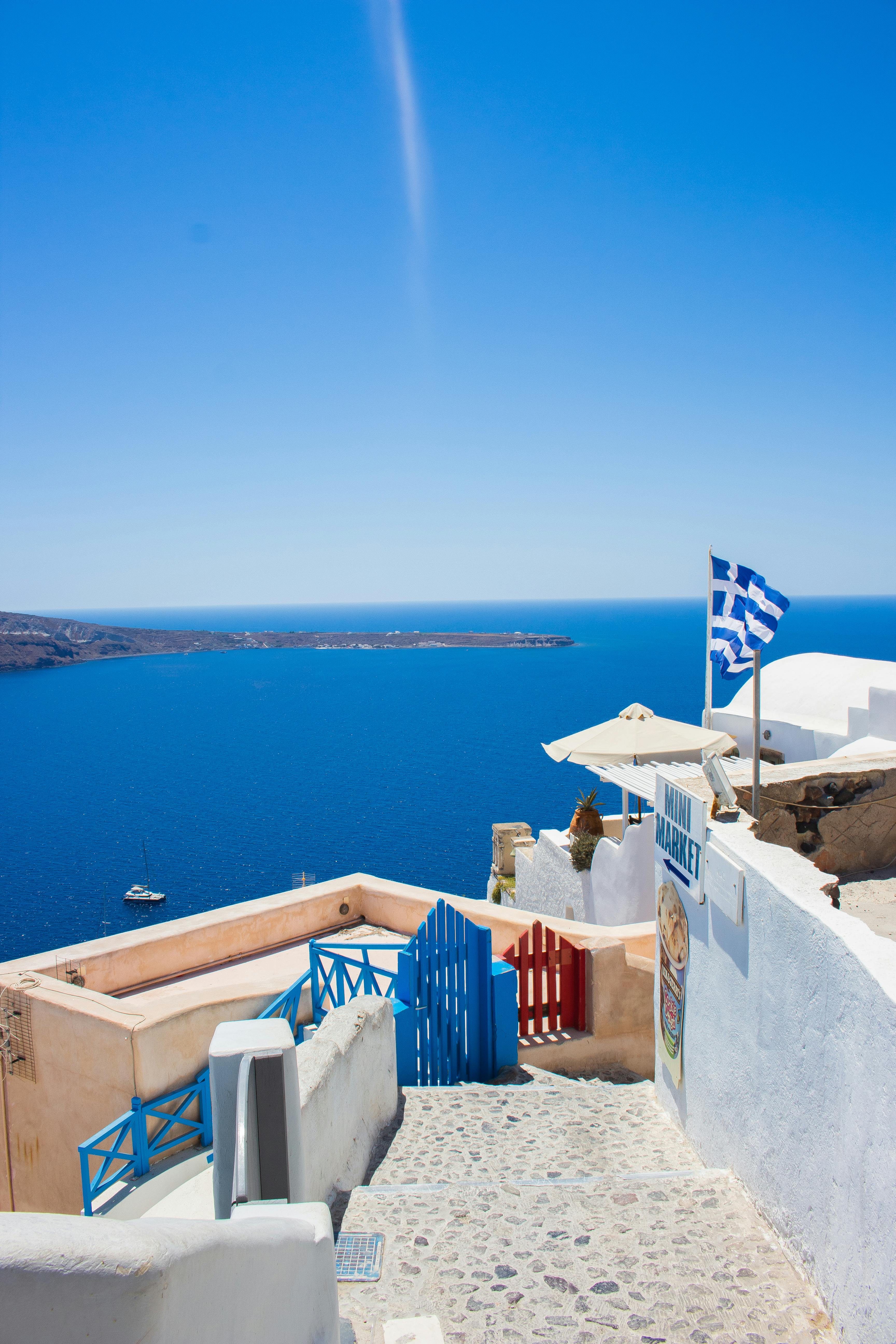 3456x5184 White and Blue Flag on White Concrete Wall Near Body of Water · Free