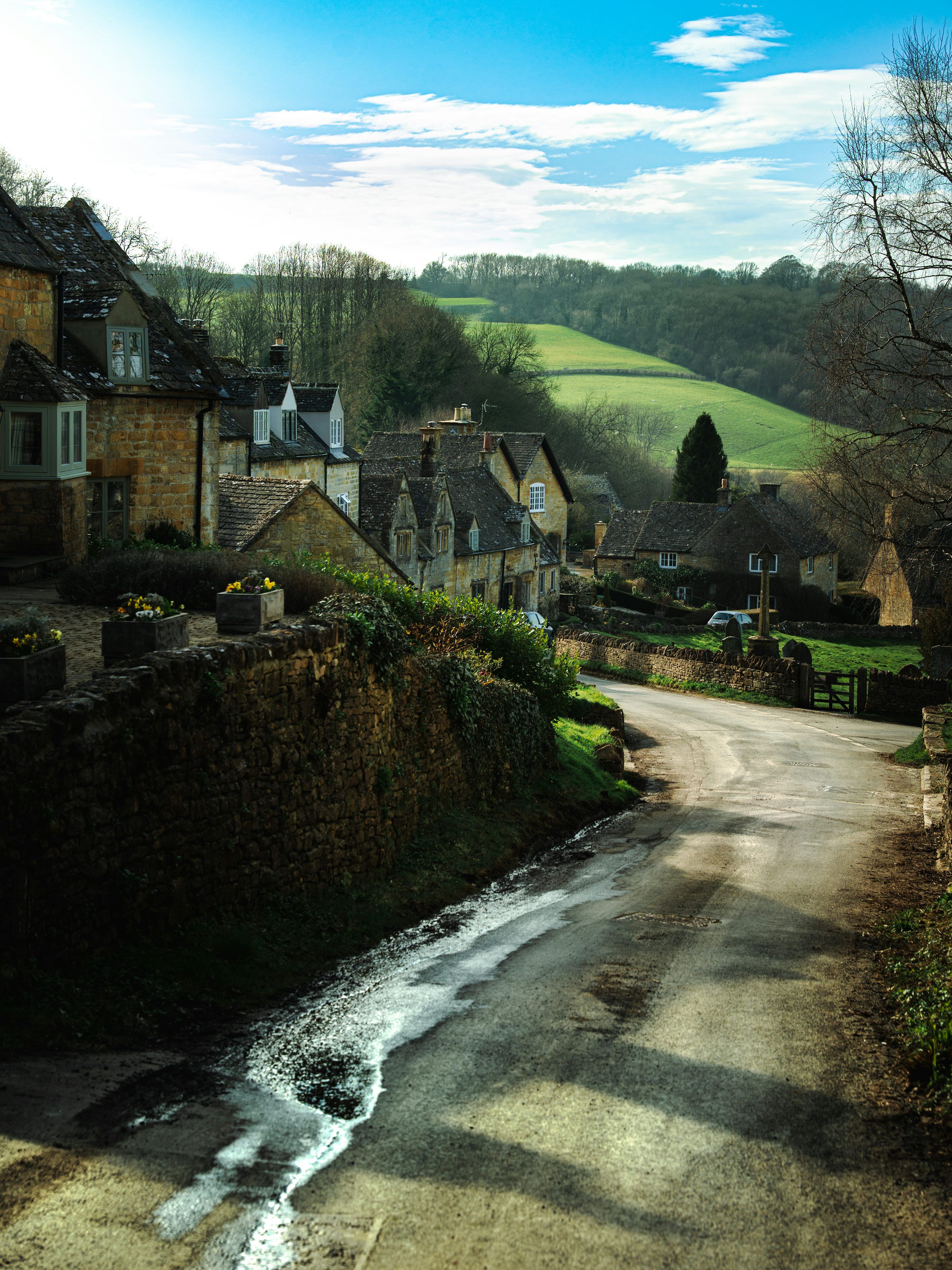 3000x4000 Quaint village nestled in rolling green hills under blue sky. photo