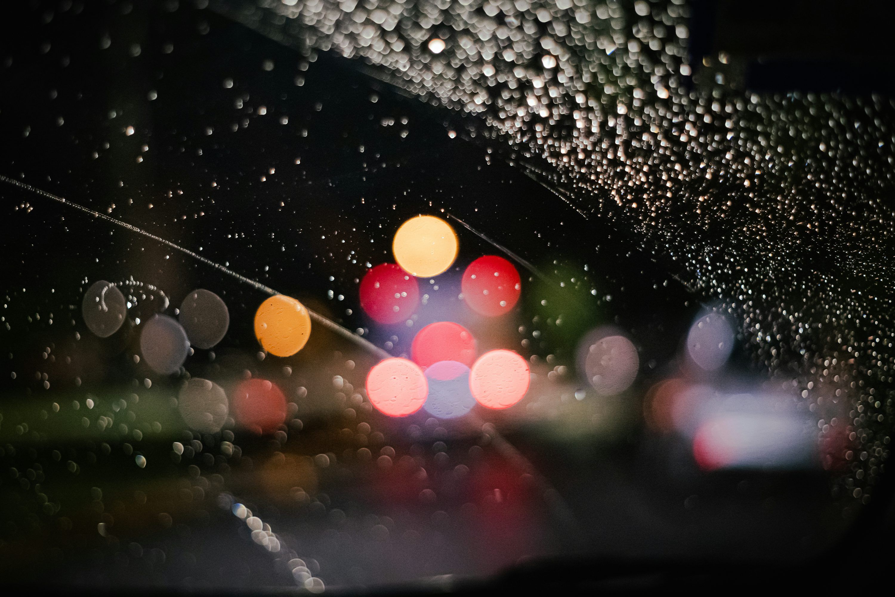 3000x2000 Rain drops on the windshield of a car at night photo