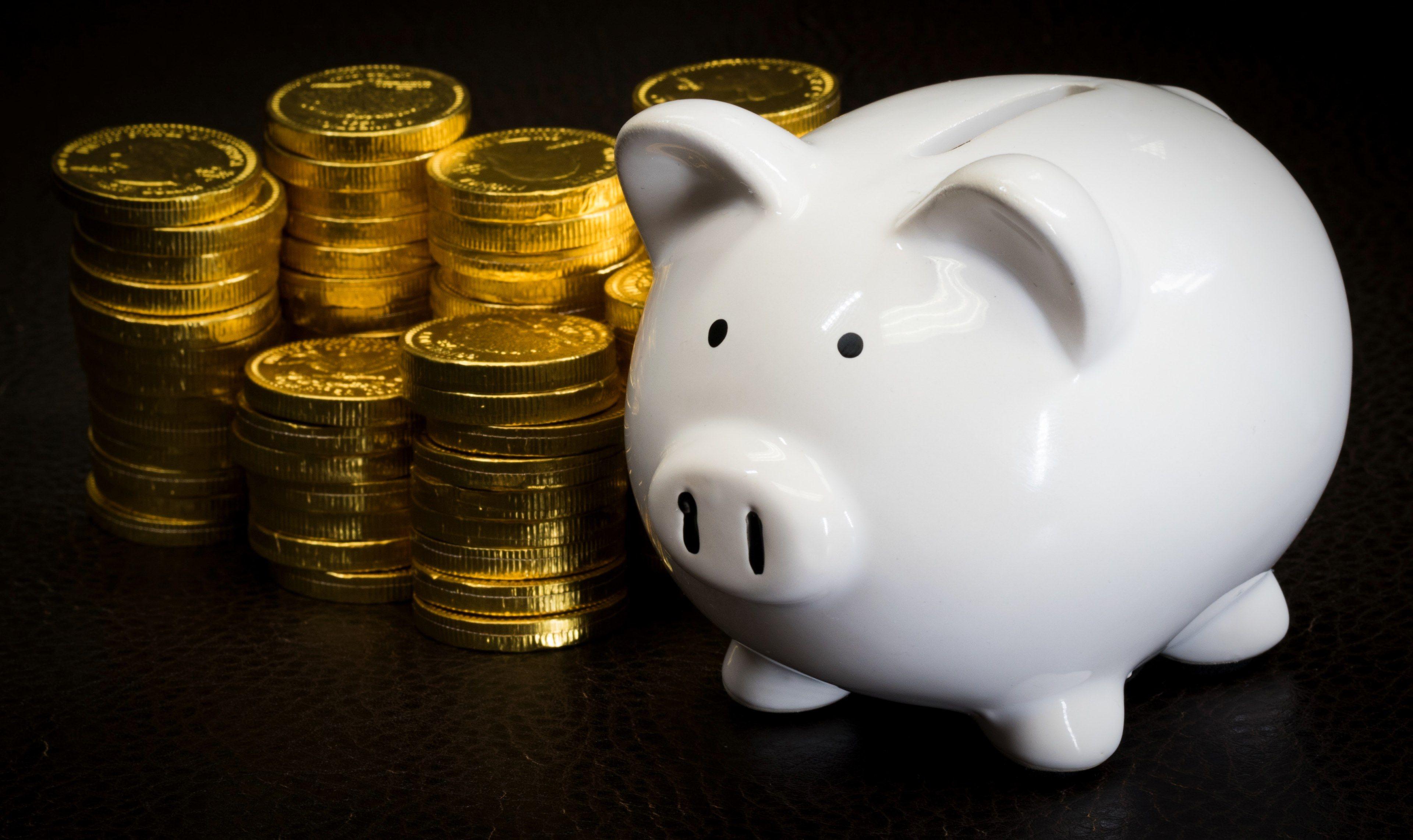 3840x2284 a white piggy bank next to a bunch of stacked gold coins piggy