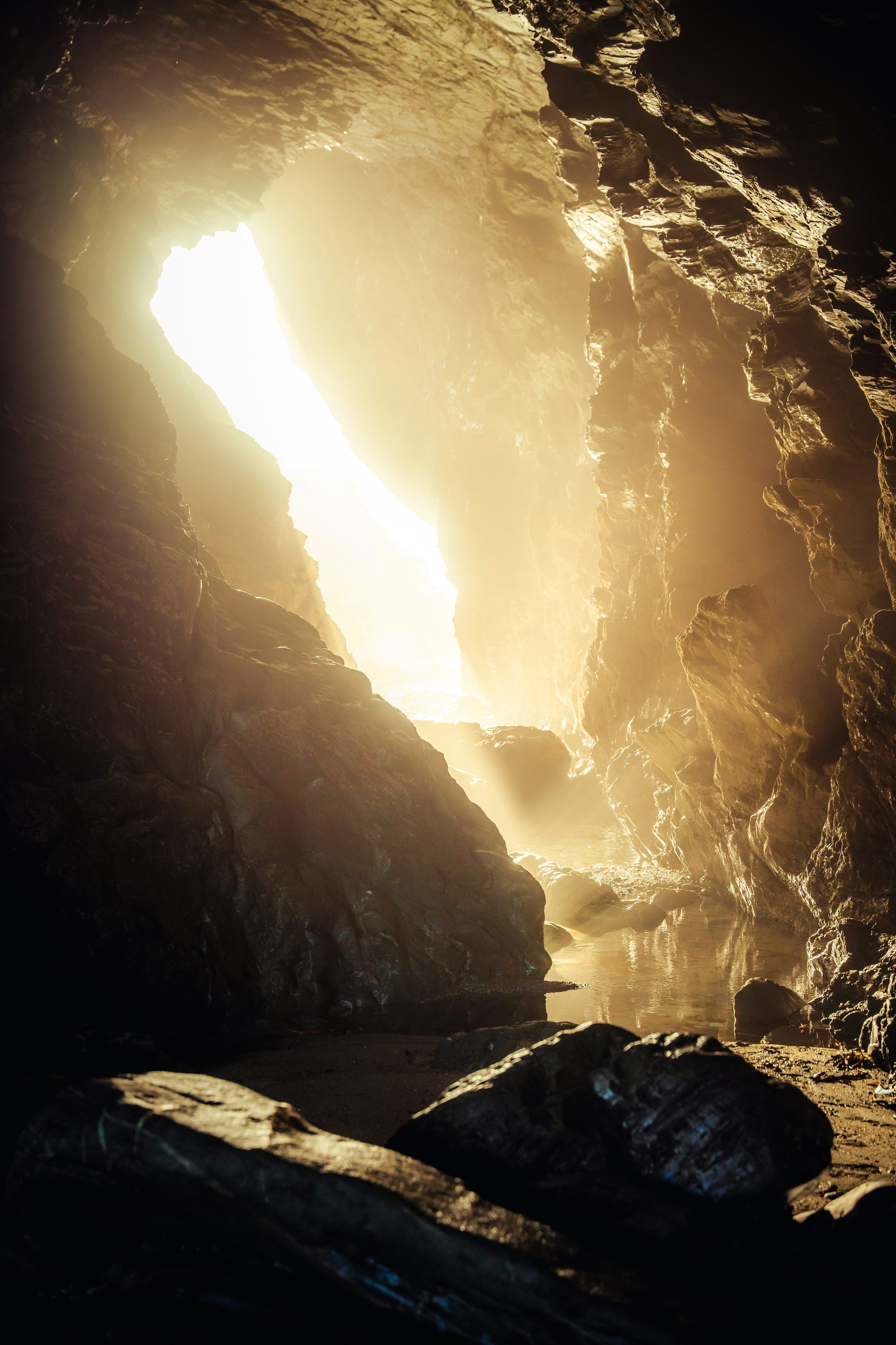 3000x4500 Sunlight streams into a dark, rocky cave entrance. photo