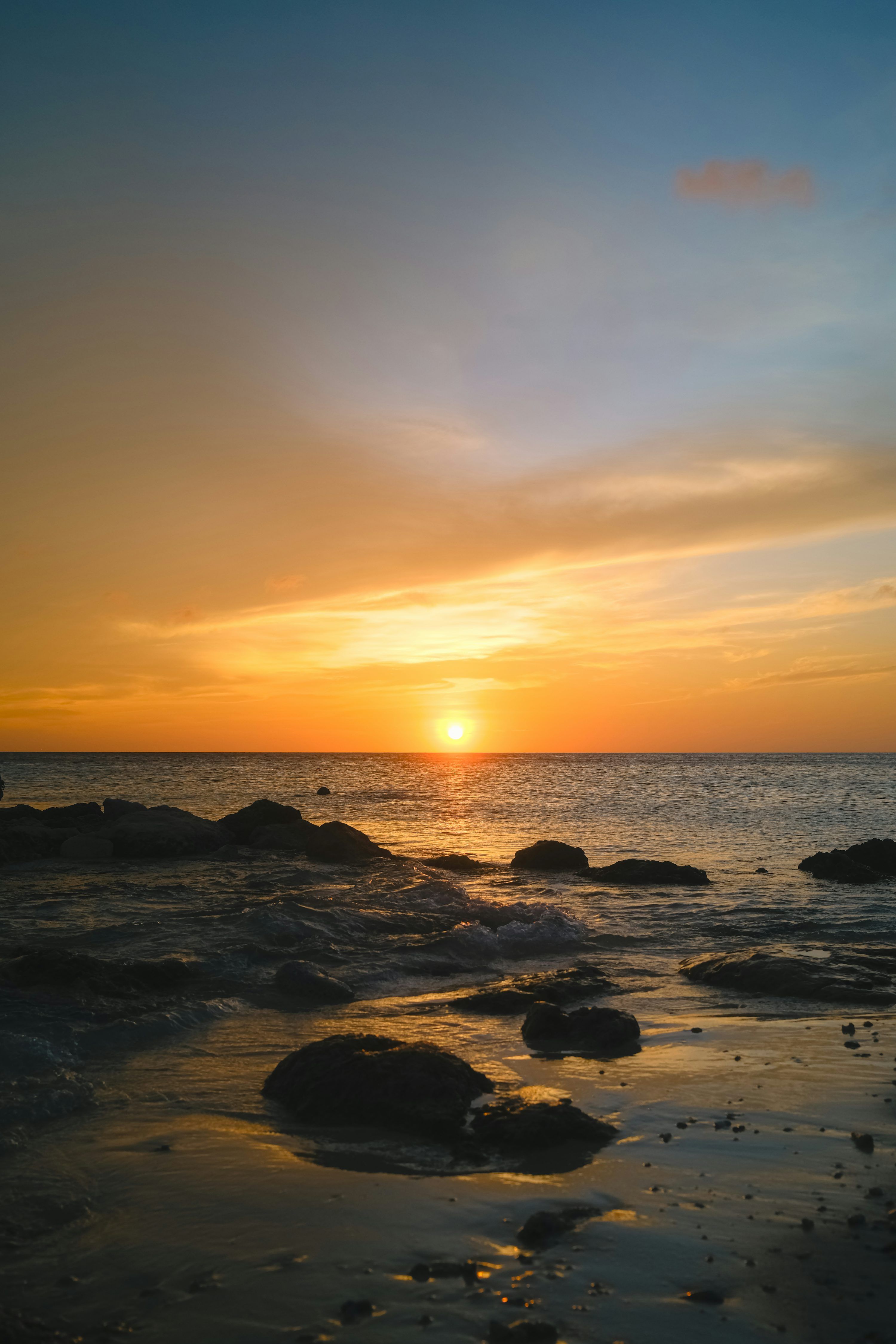 3000x4500 Sunset over the ocean with rocks on the shore. photo