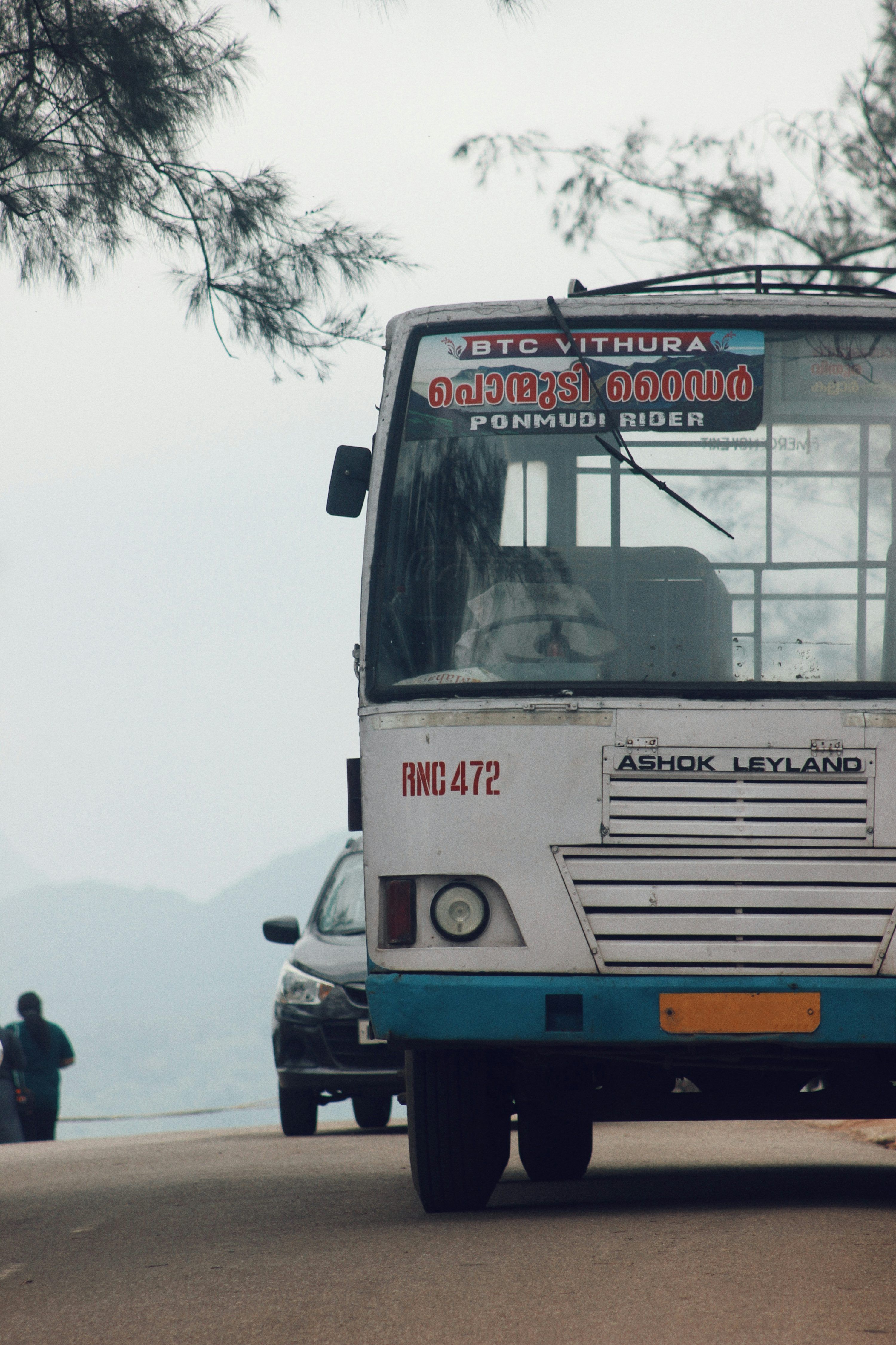 3000x4500 A white and blue bus driving down a street photo