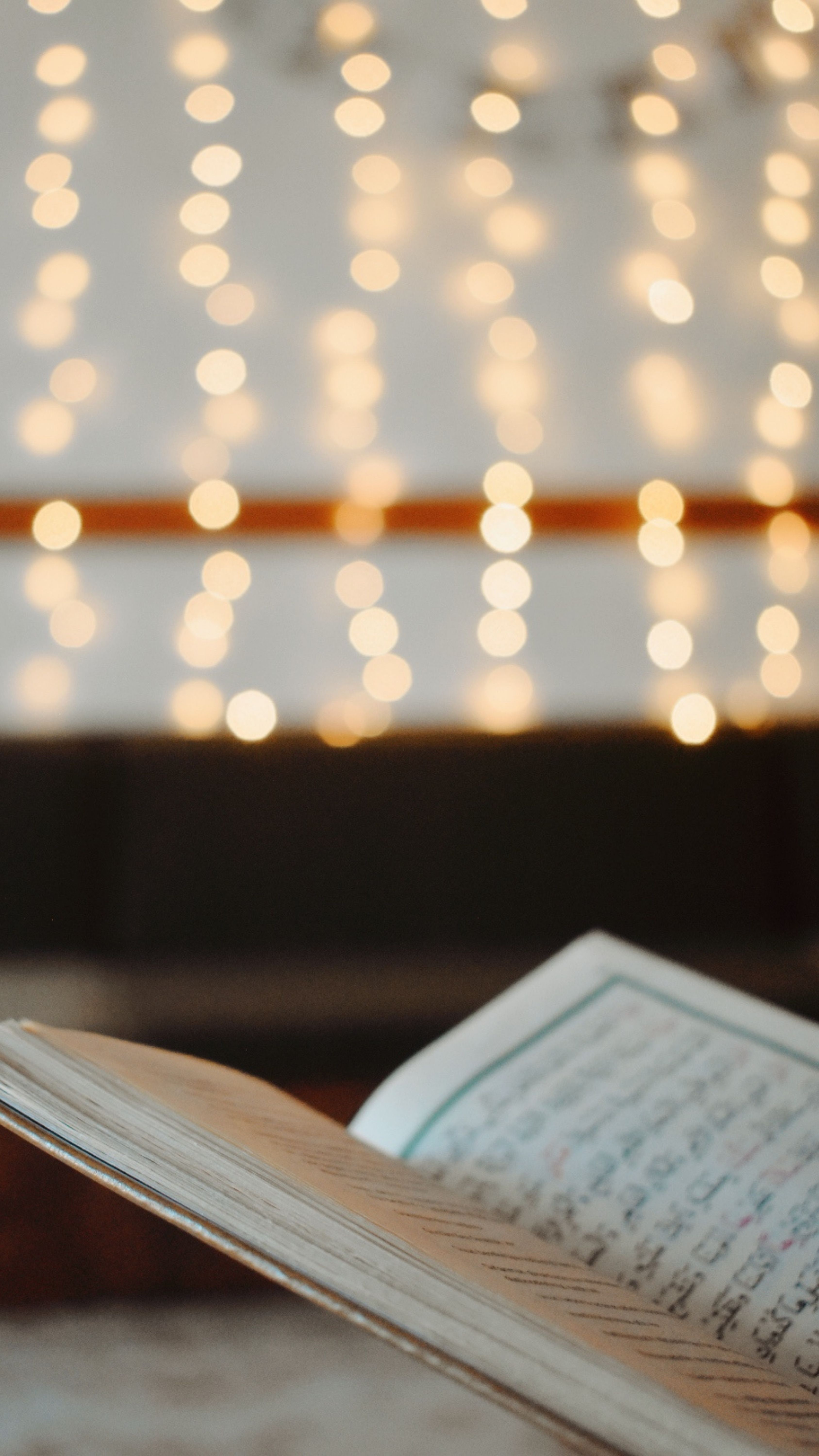 3375x6000 Blurred Lights and Open Arabic Book on Table · Free