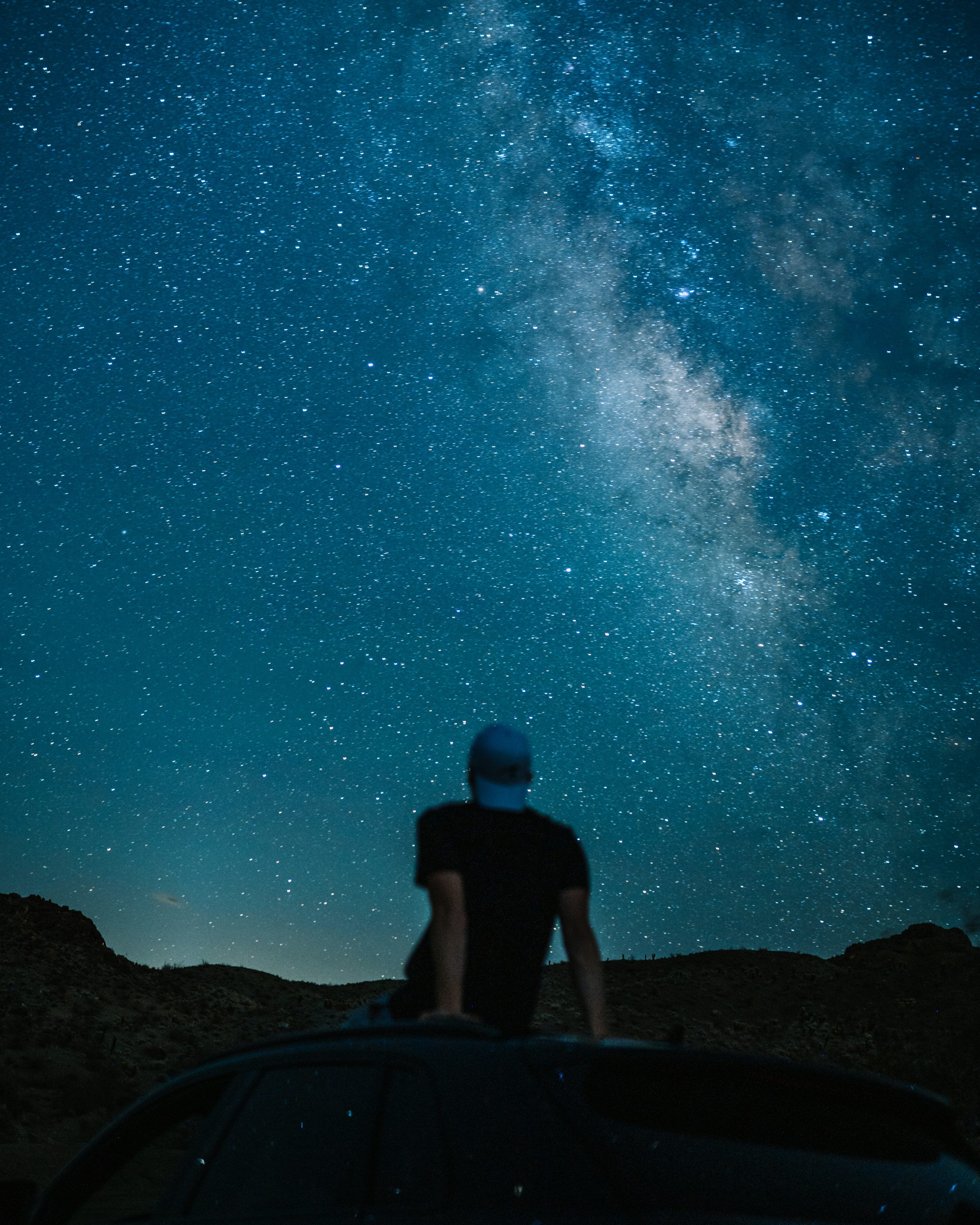 3000x3750 A person sitting on a rock looking at the stars in the sky photo